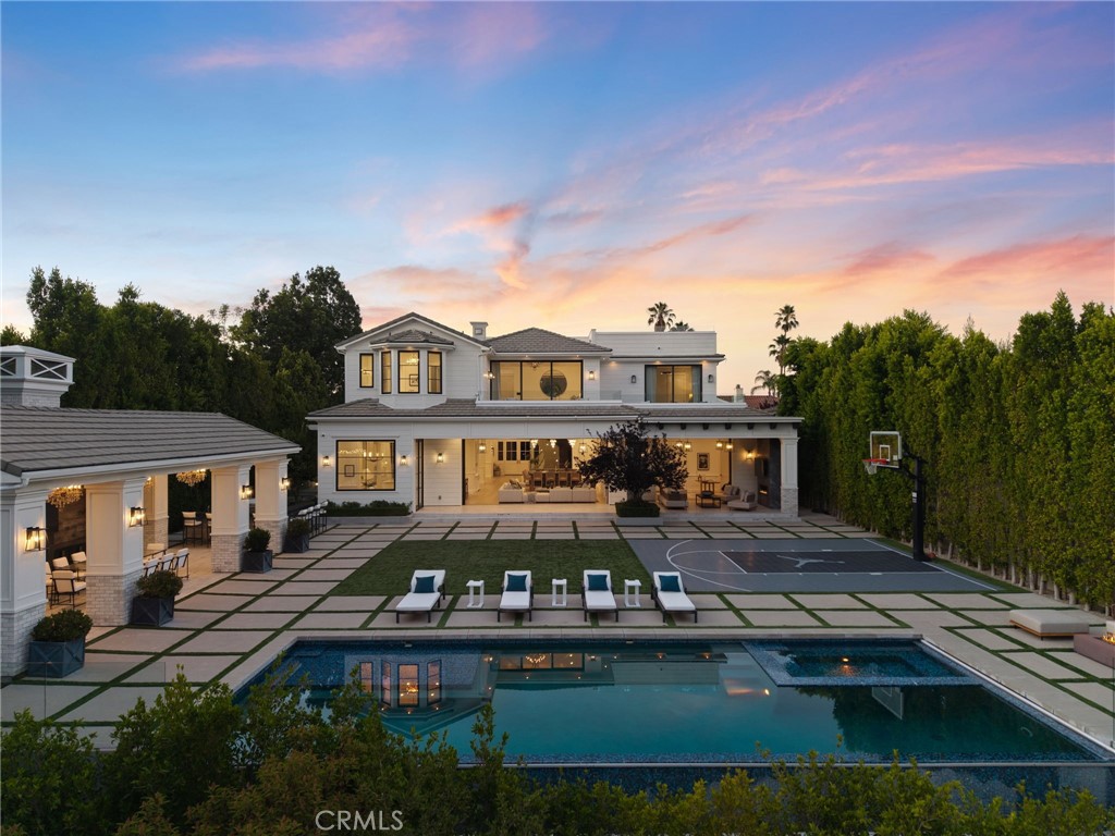 Perched in the hills of Encino on a peaceful cul-de-sac, this architectural tour de force effortlessly combines timeless elegance with modern luxury and sweeping panoramic views. Behind grand double doors, an impressive foyer welcomes you with soaring ceilings and a dramatic spiral staircase, setting the tone for the home's sophistication and scale. The expansive open-concept main level is designed for both lavish entertaining and comfortable daily living, featuring a seamless living and dining area, a stylish family room with a sleek bar, a temperature-controlled wine cellar, and dual pocket glass doors that open at the touch of a button offering a true indoor-outdoor lifestyle. At the heart of the home is a gourmet chef’s kitchen, outfitted with top-tier appliances, double islands, a sunlit breakfast nook, and a well-appointed butler’s pantry. Upstairs, you’ll find three ensuite bedrooms and an opulent primary suite complete with dual spa-like bathrooms, a custom walk-in wardrobe, and a pocket glass door opening to a large private balcony overlooking the backyard oasis. The lower level is designed for pure indulgence, featuring a glass-enclosed office, billiards lounge, plush home theater, serene massage room with a sauna, and an additional patio with direct access to the backyard. Surrounded by mature hedges for added privacy, the resort-style backyard offers a sparkling infinity-edge pool with a large spa and baja shelf, a 600 sq ft cabana, an outdoor kitchen with bar seating, and a sports court. Crowning the estate is a showstopping 1,000+ sq ft rooftop deck with commanding views of the Valley perfect for sunset cocktails or stargazing. Additional features include two main-level ensuite bedrooms, dual laundry rooms, mudroom, elevator, soaring ceilings, Control4 smart home automation, a gated driveway, and a three-car garage. Ideally located South of the Boulevard within the coveted Lanai Road School District and just minutes from the Westside, the Valley, and world-class amenities.