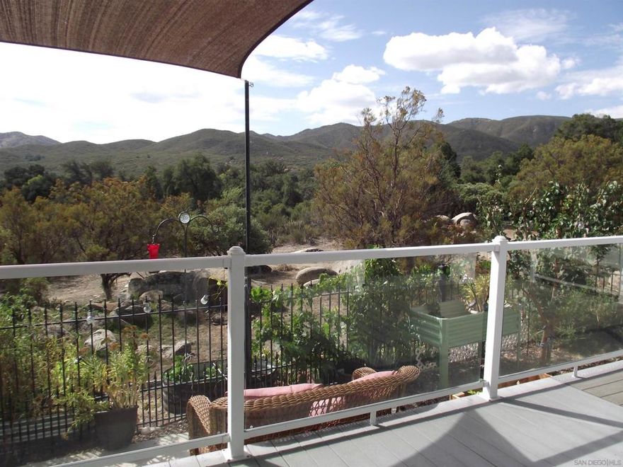 LOVELY HOME, UNIQUE FEATURES, ENJOYABLE VISTA...in the AFFORDABLE & LAND OWNED 55+ active community of Stone Ridge, in the beautiful back-country of San Diego County.  The spacious outdoor living space looks down on a wild, natural landscape, and features partially covered, expansive decking with sun shades, glass railing, flagstone patio, a plumbed greenhouse, and creative garden space.  The interior's open floor plan shares light throughout Kitchen, Dining, and Living spaces, and features wonderful upgrades.  Upgrades include a freshly & cheerfully painted Kitchen, newer appliances, luxury vinyl plank flooring, barn door opening to the Den, gated rod-iron fencing, 2-car wide carport + privacy panels along side of driveway, and a whole-house Generac generator. Creature comforts galore...gas fireplace, ceiling fans, double-glazed windows, storage alcove in Hall, spacious wardrobes, En-Suite with soaking tub, separate shower, and linen storage. Also water filtration, a private office space with a/c in garage, a ramp to front door, & on top of it all...fruit trees! Enjoy community Clubhouse, pool, spa, and fishing lake.  An easy 30-mile drive, to Temecula for shopping, restaurants, medical offices & hospital. SAY YES! And schedule a visit NOW!
