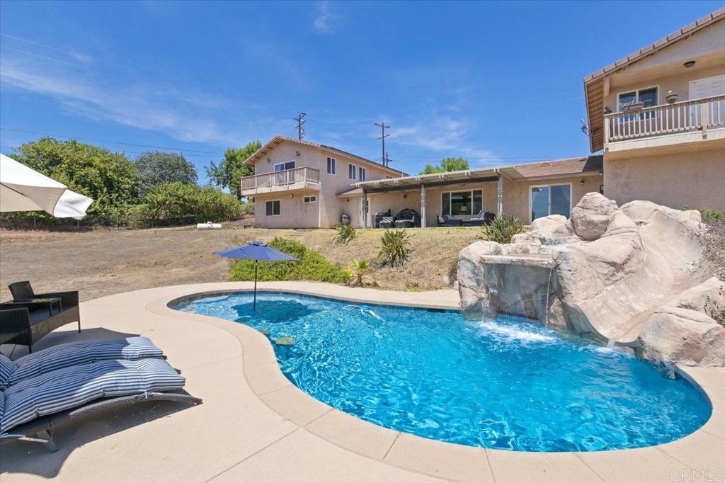 This beautifully updated 5-bedroom, 4-bathroom home in Valley Center offers the perfect blend of modern comfort, country charm, and multi-generational flexibility. Set on 1.86 usable, gated acres with sweeping mountain views, this spacious 3,768 sq ft property includes a fully equipped attached guest apartment with a private entrance. The one-bedroom, one-bath unit, approximately 800 sq ft features a full kitchen, living area, walk-in closet, and plenty of natural light, making it ideal for extended family, guests, or potential rental income. Inside the main home, you’ll find a bright, open-concept floor plan with excellent flow between the kitchen, dining, and living areas. The large kitchen is a chef’s dream, with granite countertops, stainless steel appliances, gas cooktop, a spacious double oven, dual operable skylights, and cabinetry with slide-out drawers. There’s also space for a commercial-sized side-by-side refrigerator and freezer. Natural light fills the home, enhanced by neutral paint, dual-pane windows, and multiple ceiling fans throughout the living room, dining area, and all bedrooms. The expansive upstairs primary suite is a true retreat, offering scenic views, private patio access, dual ceiling fans, and a custom built-in closet with mirrored doors. The spa-like en-suite bathroom includes dual granite vanities, an oversized soaking tub, travertine finishes, a large walk-in shower, dual skylights, and plantation shutters. Additional highlights include LVP flooring, a dining area with built-in cabinetry, built-in ceiling speakers, a downstairs flex room with double doors perfect for an office, gym, or playroom. Step outside to enjoy the sparkling pool and spacious patio with an aluminum patio cover, perfect for entertaining and enjoying peaceful country sunsets. The property also features paid-off solar, full RV hook-ups, a Tesla wall charger and 220V in the garage, and a detached third garage bay with overhead storage. For those seeking a more rural lifestyle, there’s a chicken coop, horse facilities, and mature citrus trees—all within a fully fenced and gated parcel. This exceptional property offers privacy, space, and lifestyle flexibility with easy commuting access to freeways, and just minutes from local schools, multiple wineries, and many other Valley Center gems. Whether you're looking for a private retreat, room for animals and toys, or multi-gen living potential, this one has it all.