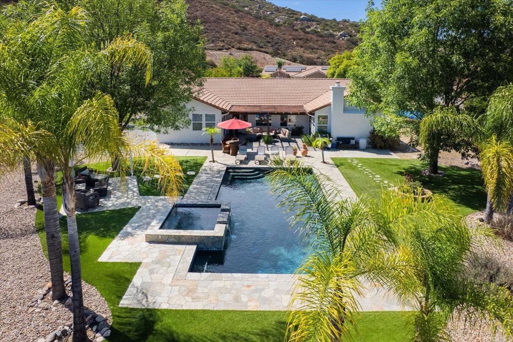 Pride of ownership is evident in this original-owner home located in the Rancho San Vicente community of Ramona. The 2,455 SQFT Ponderosa floor plan offers 3 bedrooms, 2 baths, and an optional 4th bedroom or office, with vaulted ceilings and abundant natural light throughout. The backyard is a stand out-a private retreat with a pool, spa, cascading waterfall, shaded pergola patio, and expansive views. The 0.75-acre parcel at the end of a cul-de-sac includes turf, low-maintenance landscaping, and gated RV parking. The spacious primary retreat provides direct access to the backyard and pool, dual sinks and closets, private water closet and soaking tub. Equally impressive is the remodeled kitchen, featuring quartz countertops, soft-close cabinetry, and high-end appliances: GE WiFi double oven, Bosch quiet dishwasher, Whirlpool 5-burner stove, and Whirlpool stainless steel refrigerator. Additional highlights include dual pane windows, a wood-burning fireplace, and a 3-car garage.
