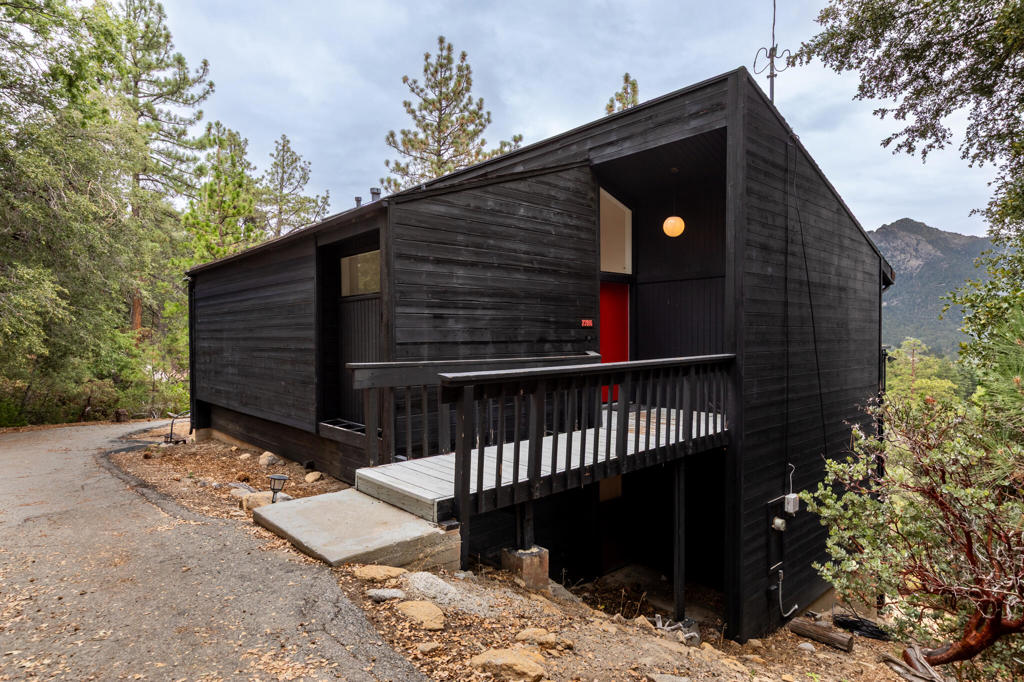 A mountain home in the modern style. c.1987. Featuring multi directional shed roof, tons of windows and skylights, natural light flows in from every angle. The home sits on a massive 3 acre lot providing seclusion and panoramic treetop views of the San Jacinto Mountains, Tahquitz Peak and Lily Rock from both levels of the house. Open living area/kitchen with soaring vaulted ceilings, beautiful pinewood floors and floating hearth are just a few features of this stunning home. Three comfortably sized bedrooms, including a very spacious master bedroom downstairs with en suite and private deck make the layout of the home very functional. All three bathrooms have been remodeled and feel clean, bright and uncluttered. The deck is a great space for outdoor dining while enjoying the incredible view. Surrounded by huge granite boulders and mature trees, this could be your cabin in the sky. Most furnishings are available with the house, negotiable through sale.