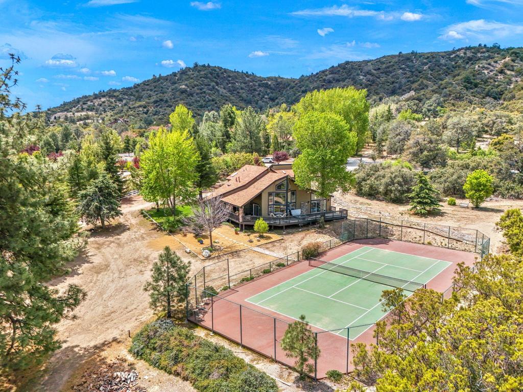 If peace, privacy, and big-sky views are calling--welcome home to GoldShot Creek in beautiful Garner Valley. This unique and inviting home features soaring windows that capture breathtaking views and flood the interior with natural light. The open-concept living room is anchored by a cozy wood stove--a must for mountain living--and showcases a warm blend of flagstone, hardwood, and carpeted flooring that adds both charm and comfort. The expansive primary suite offers a true sense of escape, with panoramic views just outside your sliding glass door, a private fireplace, and a spa-like bathroom complete with double sinks set in custom flagstone counters, an oversized soaking tub, and a walk-in shower. Every detail has been thoughtfully designed to blend rustic character with modern convenience. A spacious loft provides flexible living space ideal for guests or creative use, complete with its own full bathroom. Downstairs, you'll find a dedicated home office and an additional full guest bath, offering room for everyone. Step outside to experience the best of California mountain living. Soak in the jacuzzi under the stars, rinse off in the outdoor shower, or play a match on your private tennis court. The tennis court also has the potential to become a pickle ball court. The property also features a covered run-in shed for your horses and is surrounded by sweeping views and tranquil landscapes that deliver total privacy and peace. Whether you're seeking a full-time residence or a weekend escape, this one-of-a-kind property offers a lifestyle of serenity and inspiration--just 35 minutes from Palm Desert and 40 minutes from Temecula. The community features 26 miles or private horse riding trails, a arena, round pen and building. **Home has a assumable low interest loan**