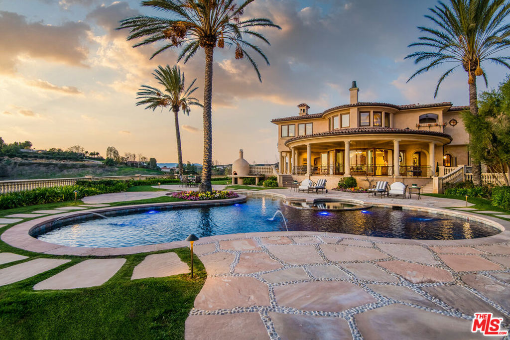 Private gates and a grand driveway lead to this regal Italian Villa situated atop a 4.4 acre promontory within the exclusive guard-gated North Ranch Country Club Estates. This opulent 6 bed, 7.5 bath residence affords 14,000 square feet of luxurious finishes, including artisan quality millwork, imported European stone, walnut floors, and hand carved glass. The gourmet kitchen offers the best in form and function, with high end appliances, exquisitely detailed cabinets, and a breakfast room that opens up to the spacious exterior loggia. An elegant library, large gym, and subterranean wine cellar/tasting room, complete the interior. Grounds are nothing short of spectacular, featuring several entertaining enclaves, outdoor kitchen with pizza oven, dining area, and pool and spa, all showcasing the breathtaking wrap around views of the golf course and surrounding mountains and hills.