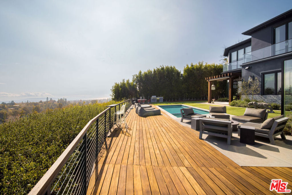 Positioned along lower Westridge Rd just moments away from Sunset Boulevard, this immaculate modern view home offers timeless design, exceptional privacy, and breathtaking vistas of the Los Angeles coastline and Catalina Island. Upon entry, a striking double-height foyer with a show-stopping chandelier leads to a sophisticated bar area, complete with seating, a wine cooler, and a dedicated lounge framed by elegant glass doors and panoramic views. The formal living room, serves as the heart of the home, boasting soaring 12-foot ceilings, expansive windows that frame captivating views, and a seamless indoor-outdoor flow, perfectly designed for both relaxed living and elevated entertaining. The gourmet kitchen, equipped with an oversized L-shaped island, top-of-the-line Wolf appliances, and a sleek waterfall breakfast bar, flows effortlessly into the expansive outdoor patio offering panoramic ocean and city views, alfresco dining, and ample space for entertaining. Upstairs, the luxurious primary suite awaits, showcasing captivating ocean views and impeccable finishes crafted for unparalleled comfort and style. The primary is complete with a fireplace, spacious spa-inspired bath with dual vanities, and an expansive boutique-style walk-in closet. This property's exceptional design is complimented by its sought-after location in the heart of Brentwood, just moments to the Westside's top-rated school districts, dining, shopping, and entertainment. This home is a rare opportunity to experience the epitome of Westside living, one you won't want to miss.