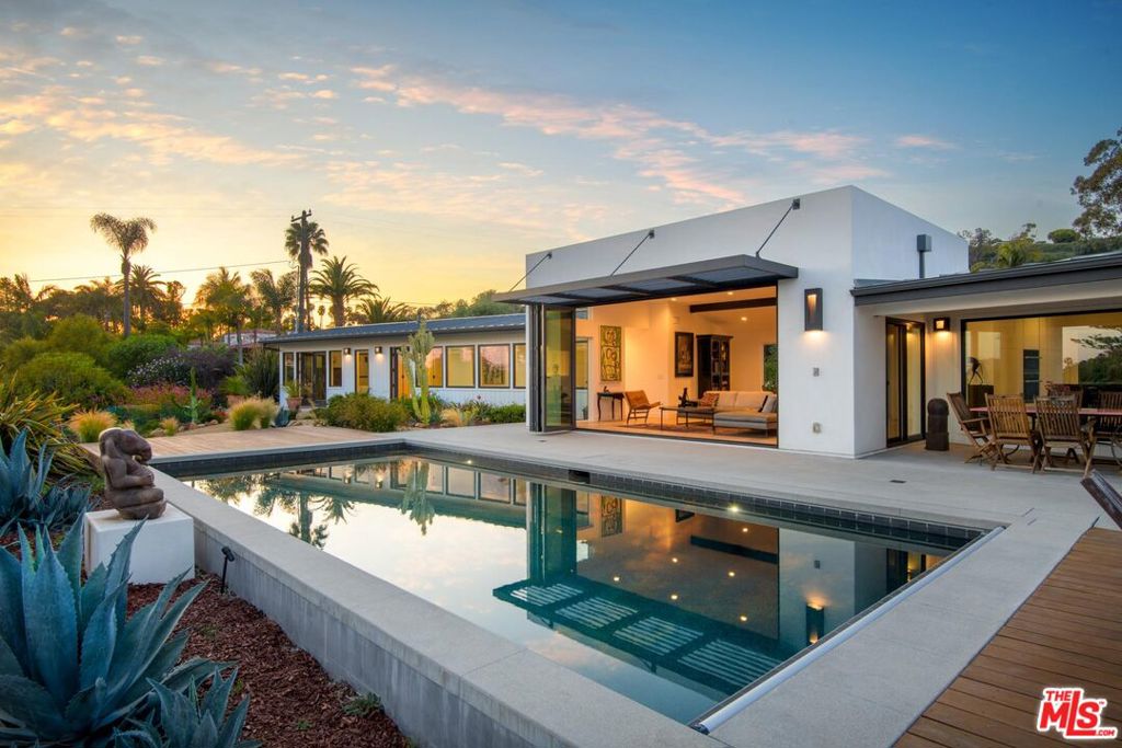 Set on just over an acre in Santa Barbara's highly desirable Yankee Farm neighborhood, 415 Yankee Farm is a design-forward, single-level contemporary home that offers privacy, light, and meaningful outdoor space just moments from Hendry's Beach / Arroyo Burro Beach. The home is oriented around a Dakari-designed heated pool, bordered by mature agaves and stone paths that connect a series of outdoor spaces designed for use year-round. A covered dining area sits just off the kitchen, while a separate patio with a built-in concrete fireplace offers a more intimate spot framed by blooming perennials and sculptural desert plants. Inside, the layout is open and natural light is constant. Wide-plank solid White Oak floors run throughout the living areas. The kitchen is fitted with white lacquer cabinetry by Armony, granite countertops, and a suite of Miele appliances including an induction cooktop, microwave, oven, and exhaust fan. Bosch refrigerator, dishwasher, washer and dryer are also included. The island serves as the functional and visual centerpiece of the space, set beneath a vaulted ceiling with exposed beams. The primary suite includes a custom walk-in closet by RD Interiors and a bathroom finished in imported Italian tile. Dual vanities by Puntotre and towel warmers reinforce an upscale, modern design. Multiple bedrooms open directly to the garden, creating a consistent connection between indoors and out. Additional features include solar panels, two Tesla chargers, an extensive irrigation system, a water softener system, and Navien tankless water heaters. Located just minutes from the coastline, upper State Street, and the prestigious Hope Ranch community, Yankee Farm offers one of the few remaining acre-plus parcels in the neighborhood and all within a short drive to the city's best farmers markets, restaurants, and beaches.