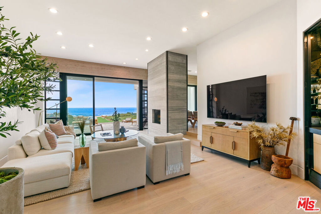 Welcome to your coastal paradise situated in a prime location on Malibu's famed Broad Beach. Beyond the entry and down a tranquil stone pathway lies a significant architectural compound, a haven of sophistication and tranquility surrounded by lush landscaping. The main residence captivates with an angular design, towering ceilings and lavish use of ceiling glass that captures the glorious sunlight to dance throughout the home. Enjoy the perfect blend of indoor comfort and outdoor serenity with elegant dining flowing to leisurely exterior lounging and entertaining. The dramatic entry foyer leads to the spacious ocean view living room with double sided fireplace, wet bar and picturesque views. The adjacent dining room provides an engaging setting for culinary delights with glass doors opening to an inviting covered patio. A lovely first floor en-suite bedroom and a media/bonus room and bath, both of which open to a peaceful outdoor seating area, complete the first floor. Ascend to the upper level where tranquility meets you in the form of two en-suite bedrooms including the primary retreat exuding unparalleled serenity featuring a two-sided fireplace separating the bedroom from the cozy sitting room. An ocean view deck, vaulted wood ceilings, a luxurious spa bathroom and large walk-in closet perfect the picture of this primary sanctuary. The guest suite retreat built over the garage has a separate entrance with a kitchenette and bath. A lower level features a wine cellar, laundry room and spacious storage room. Savor the sound of the waves from the beachfront spa or at any of the home's many outdoor seating areas, including one that directly overlooks the breaking surf. Experience the best of the Malibu lifestyle at this coastal paradise, just a shell's throw from the fabulous restaurants and shops at Trancas Country Market.