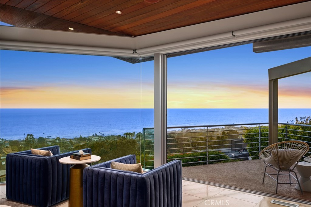 Welcome to a Mark Singer-designed sanctuary where modern sophistication meets coastal serenity. Perched in the highly sought-after enclave of Woods Cove, this one-of-a-kind 4-bedroom, 4,400 SF architectural marvel offers sweeping, unobstructed views of the Pacific Ocean, Catalina Island, and the pristine coastline of Laguna Beach. From the moment you step through the front door, you're enveloped in floor-to-ceiling ocean vistas, soft coastal breezes, and refined finishes that evoke the indulgence of a five-star resort. Thoughtfully upgraded with newly installed and fully owned Tesla solar panels, the home offers cutting-edge energy efficiency without compromising luxury. The main level hosts a breathtaking primary suite with expansive walls of glass framing the endless seascape and twinkling city lights. The spa-inspired ensuite bath features heated floors, vaulted ceilings, and timeless elegance. A true chef’s kitchen awaits with quartzite countertops and backsplash, a large central island, and top-tier appliances including a Hestan range, Liebherr refrigerator, Cove dishwasher, and built-in two-drawer refrigerator. A spacious walk-in pantry adds convenience and style. Seamless indoor-outdoor living is at the heart of this home, with a tranquil water feature leading to a large entertaining deck—ideal for sunset dinners or lively gatherings under the stars. The mid-level offers a second living area for entertaining, complete with a built-in projector, expansive ocean-facing deck, and a climate-controlled 800-bottle wine cellar—perfect for movie nights or intimate tastings. Each secondary bedroom suite is a private retreat, featuring its own terrace, entrance, and coastal views. One room also doubles as a creative studio or home office. A distinctive staircase adds architectural flair, capturing sunlight and ocean sparkle by day and golden sunsets by night. Practical luxury continues with a generous three-car garage and a full driveway, ideal for guests and car collectors. And with fully owned Tesla solar, you’ll enjoy sustainable living with reduced energy costs—without sacrificing comfort. This is more than a home; it's a lifestyle—a rare opportunity to live above the waves in timeless style, just moments from world-class beaches, restaurants, boutique shopping, and the vibrant Laguna Beach art scene.