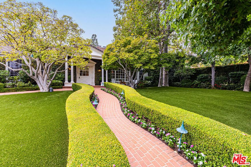 Formerly the home of Goldie Hawn and Kurt Russell, this nearly 6,400-square-foot traditional residence has been meticulously renovated, seamlessly blending East Coast charm with modern luxuries. Privately tucked away behind gates, a brick pathway, lined with manicured greenery, leads to the vine-adorned facade, welcoming guests into the formal entry. Hardwood floors and crown moldings guide you to the formal dining room on the left and the formal living room with one of the home's four fireplaces on the right. A temperature-controlled wine tasting room, converted from one of the bedrooms, is perfect for entertaining. Grand central skylights in the den and kitchen flood the home with natural light. The chef's kitchen is fully equipped with a substantial center island and peninsula, top-of-the-line appliances, ample cabinetry, a farmhouse sink, and an eat-in nook. The primary suite offers a luxurious en suite bath with a soaking tub, sauna, and custom walk-in closet. An adjoining bonus room with an additional en suite and closet makes for the perfect office or sitting room with direct access to the backyard. Three additional guest suites, all generous in size, complete this highly functional floor plan. Set on a nearly 18,000-square-foot lot framed by mature landscaping for complete privacy, the property features a swimmer's pool, multiple fire pits, a built-in barbecue, and lounging and dining areas, along with a putting green -creating an entertainer's paradise.