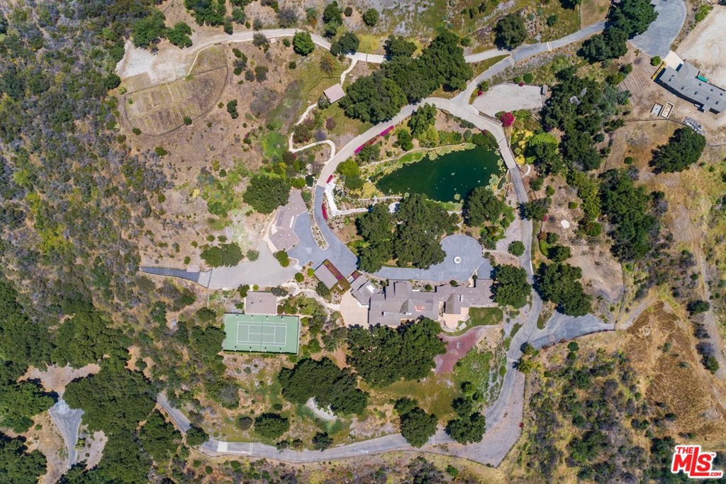 This is a remarkable, one-of-a-kind property consisting of 48 sprawling acres. Enter through a magnificent, custom gate and then up a quarter mile long, tree lined driveway to an unbelievably beautiful and secluded setting. There are currently 5 structures on site: a 12,000 s.f. main house (square footage approximate), tennis court with pavilion, separate guest houses, caretaker's unit, art gallery and studio and plenty of room for horses. In the center of this amazing property is the most serene and tranquil lake with waterfalls all surrounded by lush landscaping and expansive grounds. The property has its own well. This property is ready for the right buyer to create their own compound with infrastructure already in place.