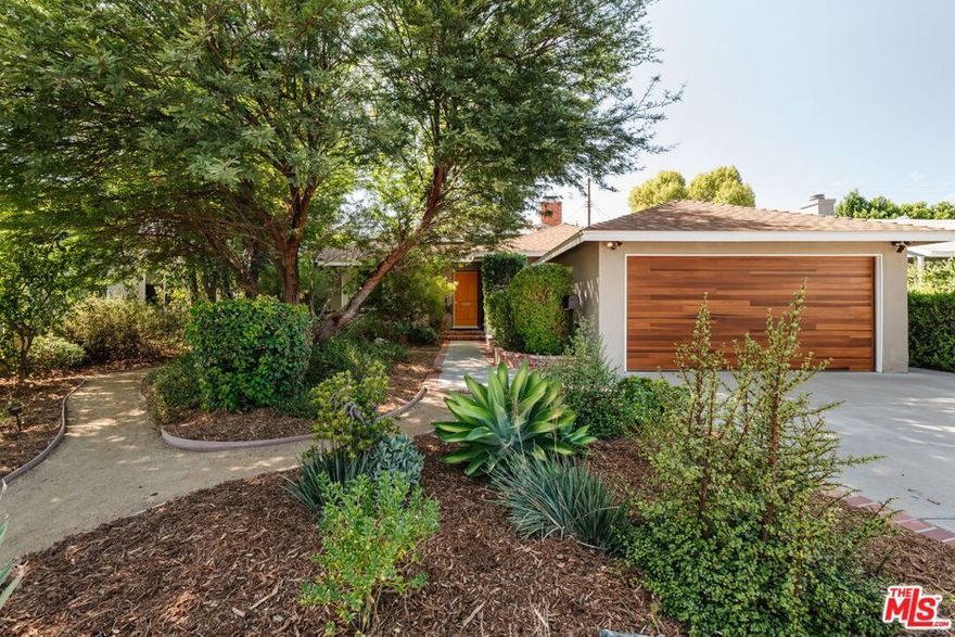 This updated and lovingly cared-for mid-century ranch jewel greets you with its lush, drought-tolerant front yard alive with color, enveloped by a chilean mesquite tree. Step into the open-plan sunny living room with wood-burning fireplace as stunning refinished original oak hardwood floors flow throughout. Updates & energy savings: FULLY PAID OFF SOLAR, newer HVAC, newer roof and garage door, Level 2 EV fast charger, copper plumbing, attic insulation, nest thermostat, water filter, and an upgraded 200-amp panel to mention a few. The remodeled kitchen features stone counters, updated cabinetry with organizer pullouts, newer Samsung and KitchenAid appliances, dining area, and separate breakfast bar that opens to the living room, perfect for morning coffee or lively evenings. The floor to ceiling pantry and laundry room are located just off the kitchen, replete with storage. A thoughtful floor plan offers one bedroom up front with en suite bath, and two more tucked down their own private wing with even more hall and closet storage. The baths have been updated, including the full bath with dual-sink vanity and gold Rejuvenation finishes. The landscaped backyard hosts a sanctuary of fruit trees gathered around a flowing fountain in your own private garden of eden. Room to host summer BBQs under the twinkle lights and still plenty of space for a pool or spa in your high-walled landscaped large lot, with a chic storage shed to store all your gardening needs. The finished 2-car garage offers flexibility of use for parking, a home gym, or home office. All just minutes from great grocery stores, shops, dining, and theaters at Northridge or Westfield Topanga & The Village (hello Costco!), yet tucked away in the serenity of its cozy Sunnybrae neighborhood. Welcome home!