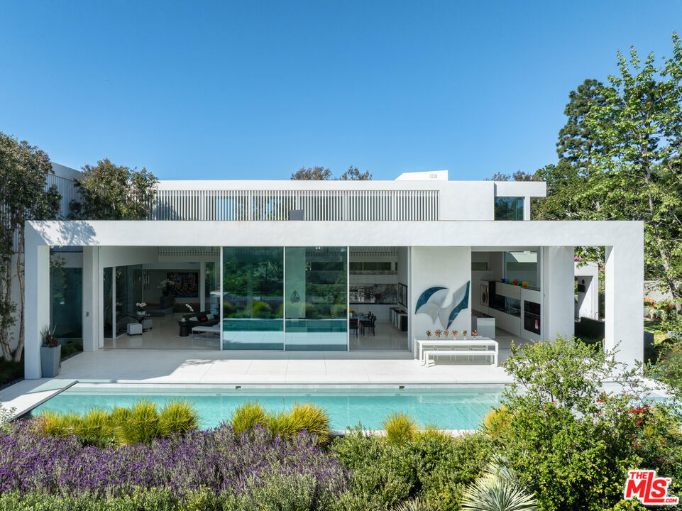 Tucked away on a tranquil cul-de-sac off lower Tigertail, the "Getty View Residence", is a striking example of contemporary design crafted by Abramson Architects and constructed in 2019. This architectural gem showcases impeccable craftsmanship, unparalleled attention to detail, and solid construction , ensuring a residence of enduring quality. Spanning 3 levels, the journey into this exceptional home begins with a dramatic entrance - crossing a serene reflecting pool and passing through an impressive pivot door. The entry level offers a temperature- controlled wine room, oversized 3-car garage, an elevator connecting all 3 levels, half bath, extensive storage, and versatile bonus spaces ideal for a home gym, theatre or creative studio. Ascend a graceful staircase of wood and terrazzo to reach the main level where breathtaking views and design meets effortless functionality. Your first impression is one of expansive openness, as large retractable doors flood the space with natural light. Shielded for privacy and energy efficiency by a striking aluminum louver facade, this level offers a sprawling great room featuring a landscaped atrium replete with a melaleuca tree. The open-concept kitchen equipped with top-tier appliances and dining and living rooms lead out to the swimming pool and lush gardens. Auxiliary rooms encircle the core of the home and include a spacious office, family room, and a fourth bedroom. A floating staircase leads to the top level and is home to the primary suite, which offers views of the Getty. The suite includes light-oak flooring, a marble-clad fireplace, cozy reading nook overlooking the garden, a luxurious bathroom with a soaking tub, and large custom closet. Two additional en- suite bedrooms are connected by a brightly lit hallway. The award-winning garden captivates, offering a sanctuary of peace and serenity. There are various sitting areas, each providing a unique view of the vibrant flora and meticulously maintained paths. Strategically placed sculptures enhance the artistic ambience of the space. Designed for entertaining, the expansive open areas can comfortably host large gatherings. The fusion of nature with modern elements creates an unmatched environment for relaxation, celebration and reflection. A true sanctuary of contemporary elegance, this is a masterpiece of design and livability. Great value.
