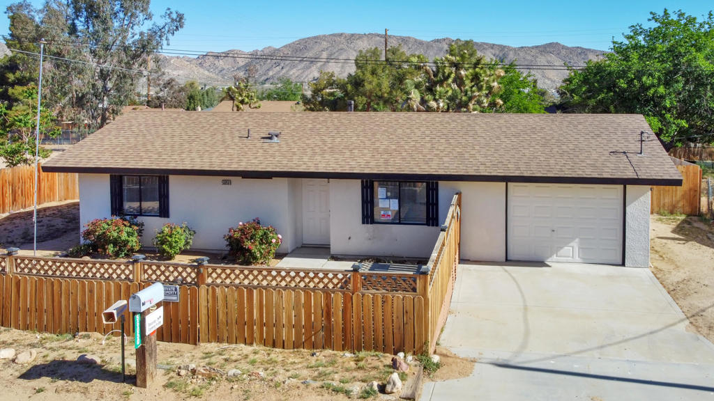 This clean and move-in-ready 2-bedroom, 1-bath home is nestled on a quiet street just off Navajo Trail, in one of Yucca Valley's most convenient and established neighborhoods. Enjoy the best of both worlds peaceful desert surroundings.Step into a bright and spacious tiled living area with fresh neutral paint, recessed lighting, and large vertical blinds that open to a covered patio perfect for relaxing or entertaining. The layout flows smoothly into a dedicated dining space, offering great functionality and flexibility.Both bedrooms feature new laminate flooring, ceiling fans, and plenty of natural light. The bathroom is clean and functional with a tub/shower combo and updated hardware. The fully fenced backyard provides privacy and scenic mountain views, with a covered patio ideal for outdoor dining or simply enjoying the high desert breeze. A 1-car garage and additional off-street parking offer plenty of space for vehicles and storage. Mature Joshua Trees on the lot add to the natural beauty of the property.Conveniently located just minutes from downtown Yucca Valley and a short drive to Joshua Tree National Park, this home offers comfort, space, and accessibility in a quiet, welcoming neighborhood.