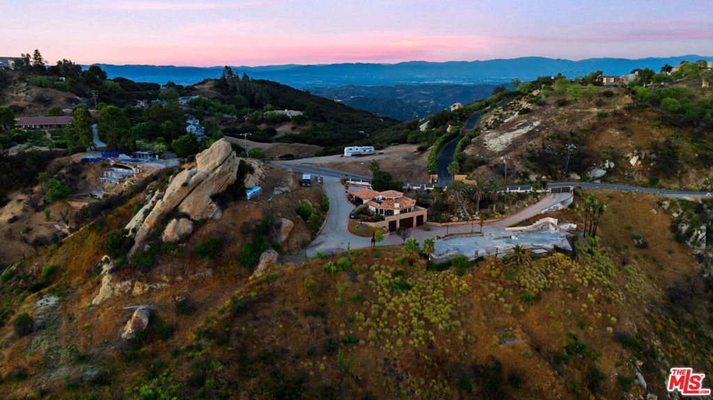 Exceptional Santa Monica Mountains Opportunity. THIS IS A FIRE REBUILD, INCLUDED IN THIS OFFERING IS A LARGE GUEST HOUSE to live in while you rebuild the fabulous estate on 9.29 acres. A Dual Parcel Estate with panoramic views perched high on coveted E. Saddle Peak, this rare offering presents a truly unique opportunity to own TWO STUNNING PARCELS TOTALING NEARLY 90 ACRES in the heart of the Santa Monica Mountains. With fabulous panoramic views stretching from rolling canyons to the Pacific Ocean, this is a dream setting for building your legacy estate. The primary parcel includes fire rebuild rights and is already improved with a well-appointed guest house of approximately 3,000 sq ft under roof. This includes a spacious, approx. 1,700 sq bottom story room garage with high ceilings ideal for a car collection, expansive workshop or other uses. Live comfortably here while you design and construct your dream home. Infrastructure is already in place for an approx. 7,000 sq ft main residence, including an existing foundation and septic system, plus original plans, helping to streamline your rebuild process. Adding unmatched value, this offering also includes a separate 79.34-acre unimproved parcel featuring its own expansive ocean view from the potential building sites. This second parcel gives you the flexibility to protect your views, create a private retreat or build another large single-family home. A rare chance to control and customize your surroundings in one of Southern California's most desirable locations. Whether you're seeking a peaceful escape, an investment with incredible potential or a canvas for your architectural vision, this dual parcel property offers endless possibilities. With natural beauty, privacy, and pre-existing infrastructure, APN #4438-039-042 at 9.29 acres is at 23000 E Saddle Peak, and APN#4438-033-074 at 79.34 acres is at 23010 E Saddle Peak