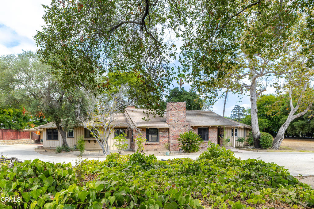 On a sweeping corner lot in Chapman Woods, this classic ranch-style fixer offers a rare opportunity for restoration or reinterpretation. With its generous proportions, original details, and expansive grounds, this 4-bedroom, 3-bathroom home captures the spirit of California living. Through the wide front Dutch door, the living room welcomes with vaulted ceilings, a brick fireplace with oversized hearth, and built-in cabinetry characteristic of the style. The adjoining family room with dining area carries forward these hallmarks with peg and groove oak hardwood floors, shiplap paneling, a built-in indoor grill and restaurant quality stainless steel bar--an authentic touch of midcentury entertaining. In primarily original condition, the kitchen is anchored by a curved diner style booth and formica table and matching bean-shaped soffit with wood moldings, offering a warm setting for family meals. A vintage in-counter blender next to updated stainless steel stove, refrigerator, and dishwasher balance originality with a modern touch. Generous storage is found throughout the home, including a walk-in pantry and built-in cabinetry and closets in nearly every room. The private wing includes three bedrooms, including a primary suite with nearly floor-to-ceiling windows that open to the expansive backyard, double closets, a dressing area with built-in vanity leading to the en suite bathroom with Dutch door, freestanding shower with glass enclosure and unique corner tub. From glass doors in the family room and main corridor, the backyard beckons with mature oaks and pecans shading a sport court and generous open space, offering endless potential for gathering, gardening, and reimagining. Outside, board-and-batten siding and whimsical dovecote detailing on multiple roof peaks distinguish this expansive, custom-designed storybook ranch property, providing an exceptional opportunity to restore, expand, and re-envision for generations to come.
