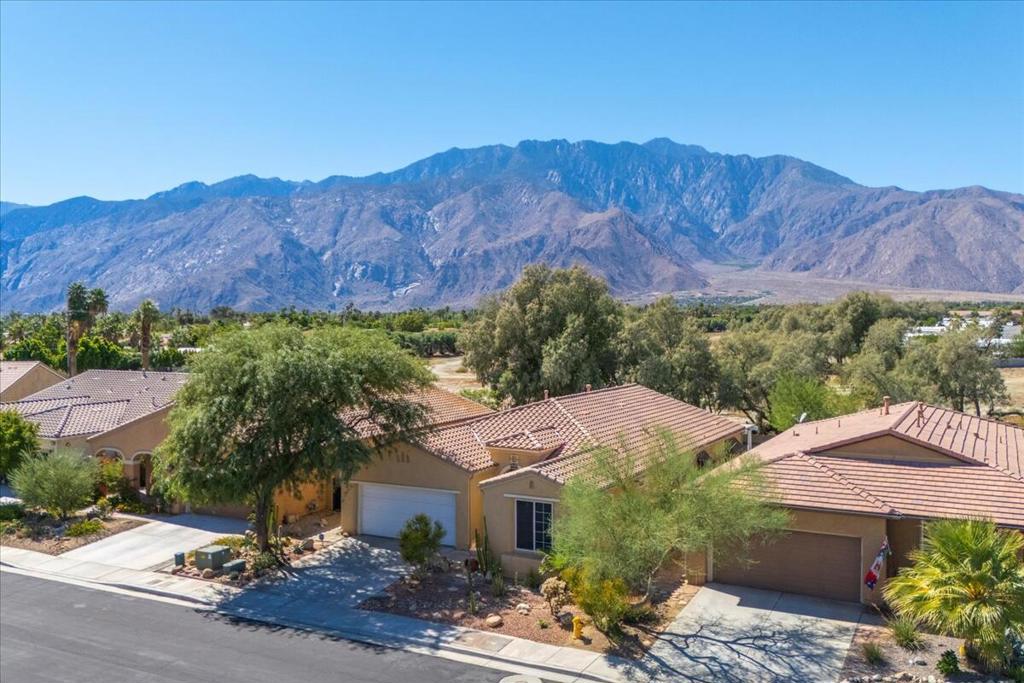 Welcome to Four Seasons, Palm Springs' premier 55+ gated community. This beautifully maintained home offers an inviting blend of comfort and sophistication with mountain views and mature desert landscaping. Step inside to find luxury plank flooring in the living room and all bedrooms, complemented by tile throughout the rest of the home. The open-concept living & dining areas feature vaulted ceilings and a gas fireplace creating a welcoming atmosphere. The spacious gourmet kitchen is designed for both function and style with SS Appliances, granite countertops, an oversized island, and abundant cabinetry. The primary suite has vaulted ceilings plus glass doors leading to your backyard patio. A generous walk-in closet also leads to a large bathroom with a double vanity, walk-in shower & large soaking tub. One guest bedroom captures beautiful mountain views, while another--with French doors--is perfect for a home office or creative space. A large laundry room with sink and extensive cabinetry adds convenience. Outdoors, enjoy a spacious patio with a full-length pergola--ideal for relaxing or entertaining while taking in the sweeping mountain views. At the heart of the community, The Lodge offers resort-style amenities including swimming pools & spas, fitness & aerobics studios, tennis & pickleball courts, a game room, library, and a full calendar of social activities. Scenic walking trails provide opportunities to stay active and connected. With low HOA dues (including Frontier fiber-optic internet) and close proximity to downtown Palm Springs' dining, shopping, and entertainment, this home combines comfort, convenience, and community. Experience Four Seasons living--where every day begins and ends with majestic mountain views!