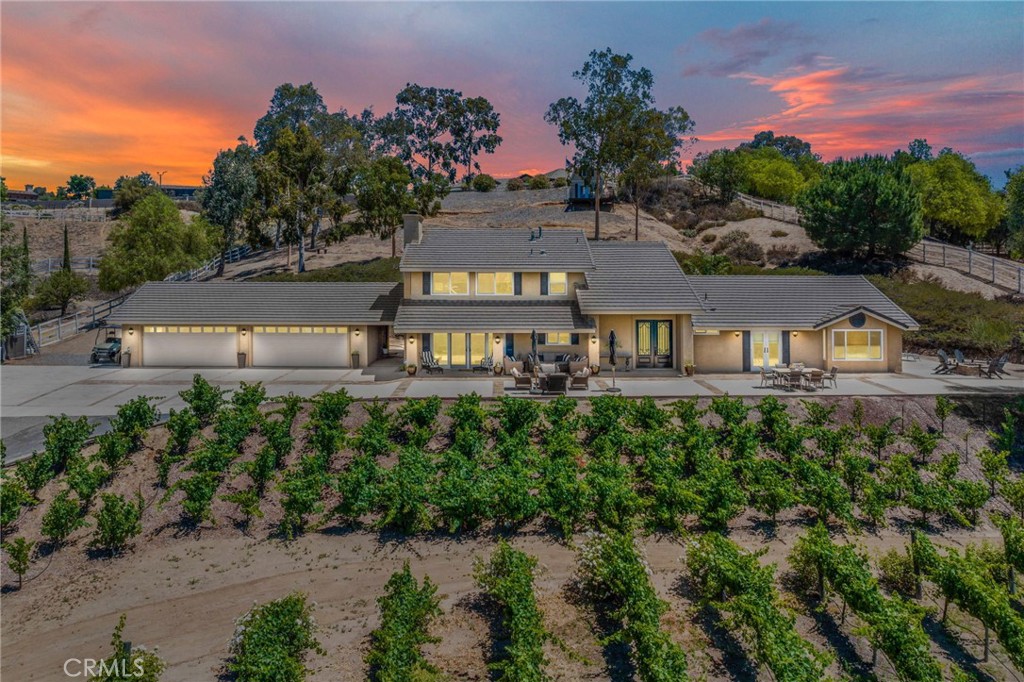 Nestled in the heart of Temecula Wine Country, this exceptional 2.28-acre estate offers the rare opportunity to live among the vines with a fully planted and producing 1-acre Petite Syrah vineyard. Located on a peaceful, quiet road yet just a short walk or golf cart ride to Peltzer, Akash, and Longshadow wineries, this property combines the best of serene country living with unbeatable access to the region’s most popular tasting rooms. Enjoy spectacular views of the surrounding vineyards and the iconic sight of Temecula hot air balloons drifting overhead.
The thoughtfully designed two-story home features a spacious owner’s suite on the main floor, plus a second full bathroom and dedicated office—perfect for remote work or a quiet study space. The chef’s kitchen includes a 2-drawer dishwasher, built-in microwave, and a separate 2-drawer produce crisper, ideal for entertaining or preparing farm-to-table meals. The climate-controlled wine room adds an elegant touch for collectors or wine lovers looking to showcase their personal reserve.
Upstairs, the home includes two oversized bedrooms, a full bathroom, and a generously sized loft/flex space—perfect for a game room, kids’ hangout, gym, or creative studio. Almost every front window in the home frames breathtaking views of the vineyards, mountains, and colorful skies, bringing a sense of peace and inspiration to daily life. From sun-drenched mornings to vibrant, glowing sunsets, this home captures the true spirit of Temecula Wine Country living.
Perched at the top of the property is a versatile bonus structure with air conditioning, heat, and custom decking—an ideal space for an art studio, office, or just a quiet place to unwind. Whether you’re hosting large family gatherings, raising children in a beautiful rural setting, or simply seeking the perfect home base in wine country, this property offers endless possibilities and timeless beauty. Don’t miss this rare chance to become part of the coveted Temecula Wine Country community.
Book your tour today