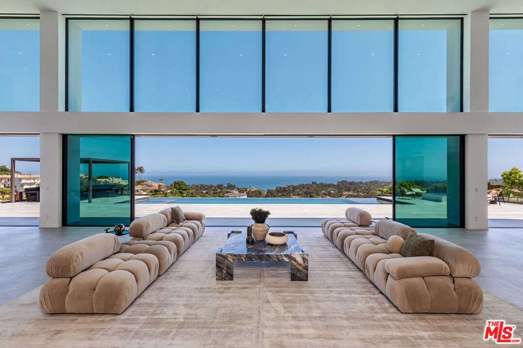 Perched on two pristine acres in Malibu, this brand-new, gated contemporary estate, spans 7,200 square feet and showcases dramatic ocean views through floor-to-ceiling glass walls. The main house features airy living spaces, including a great room with 21' ceilings that opens to a 54' long infinity pool blending into the Pacific Ocean, a seamless flow into a Leicht European kitchen and dining area, a wine cellar, study, and state-of-the-art theater. The entire top-floor primary suite offers a wraparound deck, luxurious bathroom with freestanding tub, and expansive walk-in closet, complemented by four additional ensuite ocean-view bedrooms. Manicured grounds with fire pits, fountains, and a grassy lawn lead to a BBQ pavilion with a full outdoor kitchen, fireplace, and TV, while a detached 815-square-foot guest house mirrors the estate's stunning views. Complete with an elevator, Control4 automation, camera security, a 4-car garage, and a gated motor court, this architectural masterpiece redefines coastal luxury.
