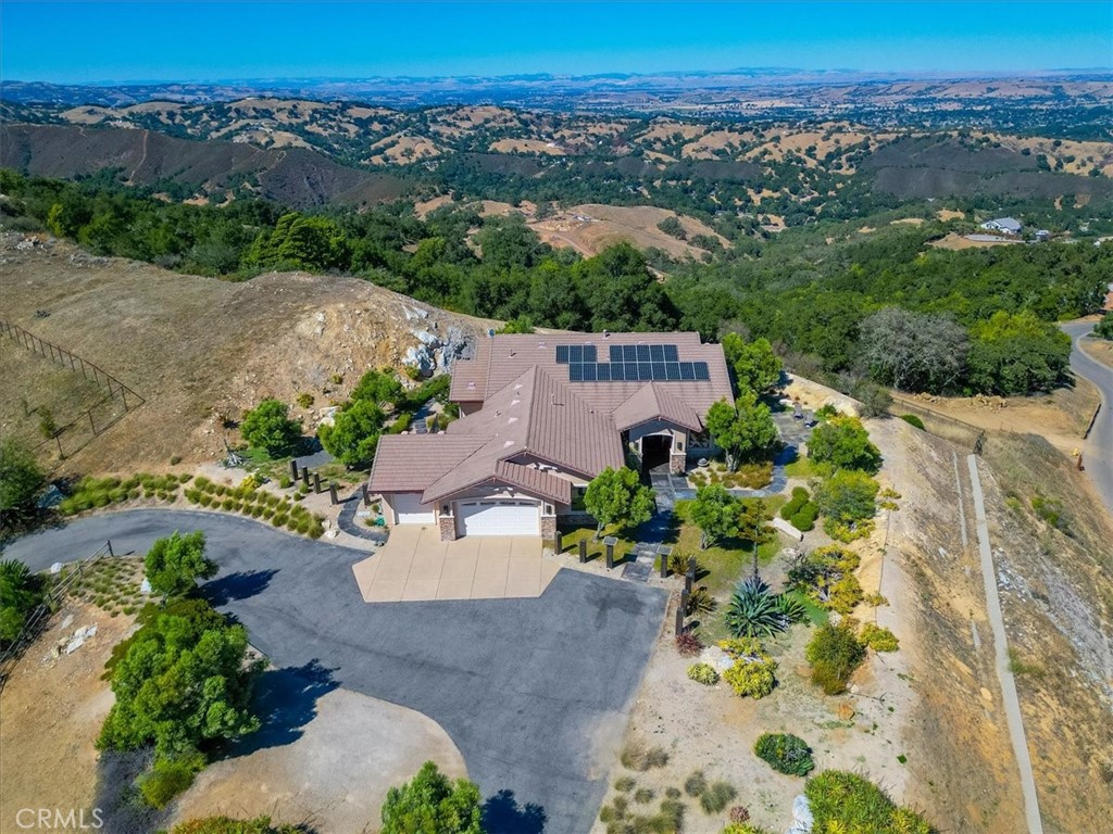 Luxury meets laid-back Central Coast living in this spectacular hilltop retreat, tucked away in the prestigious Oak Ridge Estates. With unobstructed 360° views of the Santa Lucia Ridge, rolling valleys—and even glimpses of the Pacific Ocean—this home offers a truly elevated lifestyle.
Designed for both elegance and ease, the expansive layout features soaring vaulted ceilings, travertine and hardwood floors, and multiple living spaces including a sunlit great room, a cozy family room with fireplace, a formal dining room, and a charming breakfast nook. The gourmet kitchen is built for serious cooking and casual gathering, complete with a large island and breakfast bar, built-in desk, and abundant cabinet and counter space.
The luxurious primary suite is a private sanctuary, boasting its own fireplace, custom built-ins, dual walk-in closets, and a spacious sitting area—perfect for quiet mornings or evening wind-downs. Smart home features include Nest temperature control, whole-house fire suppression, and an EV charging station, all powered by an owned solar system with battery backup.
Outside, the amenities continue with a fully equipped outdoor kitchen, BBQ, and wet bar—ideal for entertaining against a backdrop of unforgettable views. Beautifully landscaped with low-maintenance finishes, this is resort-style living with the privacy and space you crave.