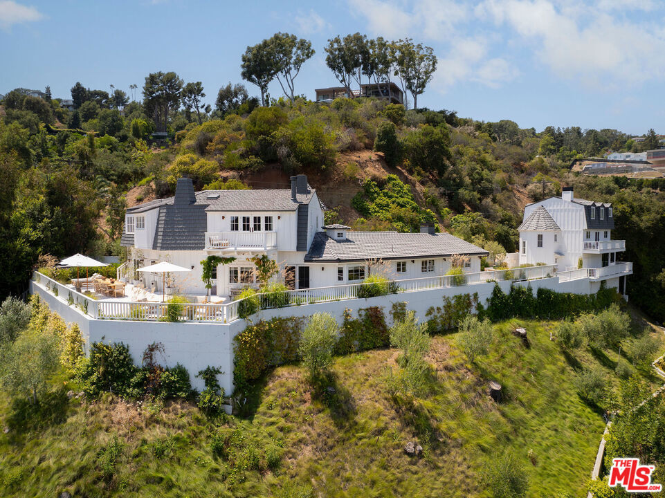 Breathtaking designer-done farmhouse located in renowned and highly coveted lower Mandeville Canyon. Nestled among LA's elite, this celebrity enclave offers the very best of Southern California living. With striking, panoramic canyon views from every room, this enchanting home is sure to impress even the most discerning of clientele. Unrivalled privacy and exceptional tranquility are just a few of the many features that define the uniquely captivating lifestyle offered at 13240 Chalon Road. Fully renovated and meticulously maintained, the home is finished with the highest quality designer touches - where no expense was spared in the pursuit of elegance. Perched on a private hillside knoll, the estate includes a 4-bedroom main residence, plus a separate structure housing a two-car garage, top-tier fitness center, and two-story guest house with full kitchen and lofted bedroom. Romantic primary suite boasts moody fireplace, steel-framed office nook, and a private balcony overlooking the canyon. The open-concept kitchen/family room merge seamlessly into one bold, architectural space perfect for both daily living and entertaining. Outdoor amenities include multiple dining and lounge areas, a sunken fire pit, SwimSpa pool, and lush landscaping - all with sweeping canyon views. A truly one-of-a-kind offering for the buyer seeking it all: style, views, privacy, quality, and a blue-chip location in the heart of the city. (Property may be available for purchase fully furnished as well - please inquire for more information)