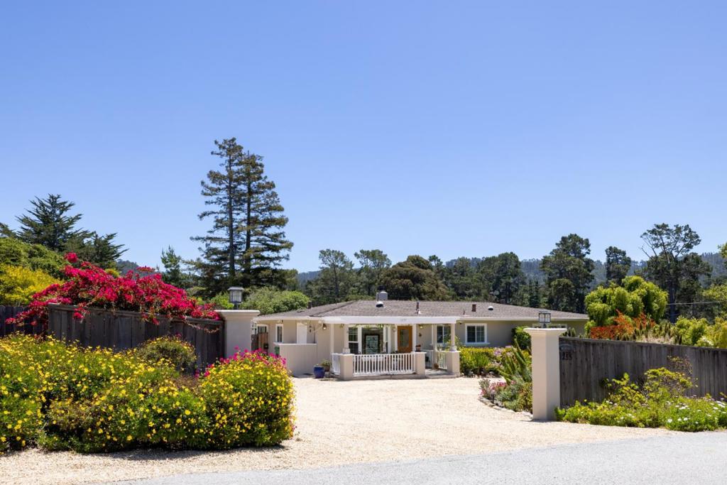The grounds of this property swirl around a lovely ranch home in a dazzling profusion of color you can see and sense from nearly every room. Violet tubeflowers, roses, and daisies mingle freely with endless varieties of green plants, fruit trees, and vibrant flora. Passing through an arched trellis, stroll along the dirt paths that wind through the gardens and orchards, stopping to admire a Japanese footbridge or greet a happy gnome hidden somewhere beneath a bush. Half an acre of brilliantly cultivated land is yours to enjoy here, ensuring privacy and making you feel you've stepped into a world all your own. Inside, discover a flexible layout with five bedrooms. An ADU with one bedroom, a kitchen, and a private patio could function as a guest suite or an excellent source of rental income. Another bedroom sports its own kitchenette and opens onto a covered deck with steps leading into a secret mini garden surrounding a spa tub. There is a bonus office -- and a front living room with elegant bay windows, built-in bookcases, a fireplace, and sliding doors that allow it to be left open or enclosed. You will find ample secure parking for an RV, boat, work vehicle, or anything else. "Whatever you desire" is the name of the game at this property with superb features and loving energy.
