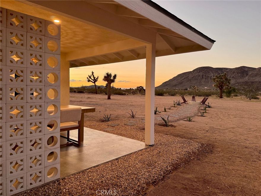 Welcome to 59676 Mitch Rd, where Bohemian Flair meets Desert Elegance. This gorgeous turn-key property has been completely remodeled with every feature intentionally chosen to bring you the perfect airbnb, desert home or weekend retreat. This house showcases 3 bedrooms, 2 bathrooms and 5 ACRES OF LAND with stunning panoramic desert & mountain views. Inside you'll find sleek concrete floors, tasteful decor & furnishings, rounded archways, recessed lighting and large windows that let in an abundance of natural light. The warm and welcoming living room flows effortlessly into the awe-inspiring kitchen and dining area complete with designer-style tile backsplash, bright quartz countertops, beautiful modern cabinetry, high-end FORNO appliances and bar seating. Each bedroom is well appointed with mini-splits for year-round comfortability, closets with custom built-in shelving and 2 of the 3 bedrooms adorn french doors that lead to their own private outdoor patios. Both bathrooms boast spa-like showers with sophisticated tile, glass panels and lovely new vanities with clean, modern finishes. The finished garage has been transformed into the ultimate hangout space equipped with a bar, wine fridge, sink, additional cabinetry, a mini-split and a cozy elevated lounge area (there is even a stacked washer/dryer for added functionality). It doesn't stop there; the serene outdoor living space includes a lovely covered patio for outdoor dining, an outdoor shower with a rainfall shower-head, ample space to entertain or relax around a firepit on a starlit summer night. Not to mention, there is more than enough room to build/expand and/or store all your desert toys! This exquisite property is located close to numerous desert attractions like Lander's famous Goat Mountain hiking trails, Giant Rock, La Copine, The Integratron, and only 15 mins from downtown Joshua Tree but still far enough away to fully immerse yourself in all the peace & tranquility this desert home has to offer. Come take a look & let the desert's allure do the rest. Your new desert home or weekend retreat awaits.