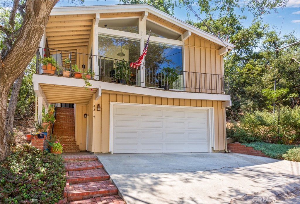 Light-filled mid-century post and beam retreat nestled in the hills of the Santa Monica Mountains. Floor-to-ceiling windows and soaring open-beam architecture bring natural light and sweeping views of mature oaks into the main living space. Located south of Ventura Boulevard close to the Woodland Hills Country Club golf course—with quick access to Woodland Hills shops and restaurants.
Remodeled interior features engineered wood and ceramic flooring, classic fireplace, nestled book nook, and sliding glass door opening to deck. The thoughtfully designed kitchen offers quartz countertops, custom soft-close cabinetry, premium appliances, recessed lighting, and dimmable under-cabinet lighting—combining function and elegance.
Two primary bedroom suites on upper level, each with beautifully remodeled bathrooms featuring Kohler fixtures, walk-in showers, and soft-close cabinet doors. Utilities have been upgraded, and home includes a large two-car garage, stylish security entry, and structural improvements such as shear walls and bolting—providing peace of mind in a timeless, private Woodland Hills setting.