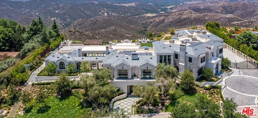 Perched in the prestigious double-gated Estates at The Oaks of Calabasas is this newly constructed magnificent modern French provincial estate. Spread over 1.65 Acres the home has countless custom features and finishes including antique wood beams adorning the ceilings paneled walls & stately millwork and wide-plank walnut wenge & oak floors throughout. The double-height foyer leads you to an open and airy interior with high ceilings and sensational details. An elegant great room faces a magnificent chefs kitchen complete with an inviting eat-in nook. Expansive accordion doors open to an outdoor oasis with an oversized pool/spa sports court lush lawns serene atrium & goldfish pond rose garden conservatory pergolas firepit & a charming orchard & vegetable garden. An exquisite primary suite with an expansive view off the private balcony features a luxurious bathroom with Borghini marble and custom vanities. The subterranean level features a 15-seat theater wine cellar and a rare 9+ car garage with a street entrance. This extraordinary home is at the pinnacle of prestige & lifestyle with breathtaking views of the serene  Santa Monica Mountains.