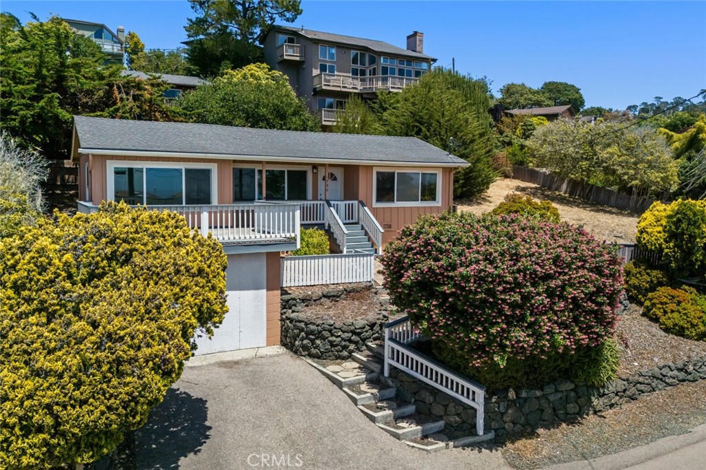 Imagine sipping morning coffee while watching the Pacific surge just beyond the coastal slopes of Rancho Marino! Positioned on one of the town’s most iconic streets, this 2-bedroom, 2-bath hillside home delivers stunning ocean views from its wide windows and expansive front deck.
Inside, the living room features classic wood panel accents that add character, while the kitchen, with its breakfast nook, captures morning light. A versatile office offers room to work or unwind. Downstairs, a converted garage extends the layout with a second bedroom and bath, and a relaxed family area ideal for guests or weekend movie nights. The utility corner includes laundry hookups, and a fenced yard is ready for creative landscaping or laid-back BBQs under the trees.
The house needs some care, but its potential is matched only by its location, with panoramas of the sea, trees, and sky. Even better, it includes an adjacent 3,500 sq ft lot sold as a package. Close to Fiscalini Ranch Preserve and nature’s ever-changing beauty, this is the heartbeat of Cambria. Come discover what makes this place unforgettable!