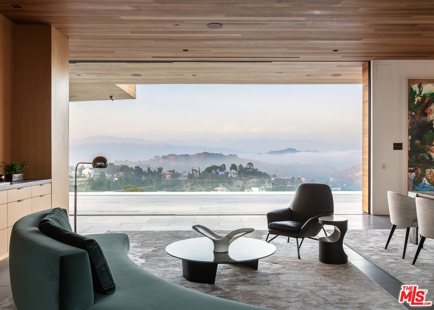 Escape to a world of utmost tranquility & seclusion, at the architectural marvel that is Carla House. Meticulously crafted by famed architect, Noah Walker, this masterpiece was impeccably designed to frame the awe-inspiring from Griffith to the Hollywood sign w/2 wings anchoring a 2,000SF rooftop deck. In Trousdale Estates, this one-of-a-kind home spans approx. 20,000SF on 1.2 acres. Open floorplan is accented by disappearing walls of glass for indoor/outdoor living. Gourmet kitchen w/dual marble islands, wine cellar, white oak cabinetry & Gaggenau ss appliances. Lux master w/leather wall, lounge, balcony, decadent bath, rain shower, soaker tub, skylight, dual closets w/extensive built-ins & vanity. Features include movie theater, fitness studio, wellness center, office, elevator, service kitchen, maid's quarters, 5+ car garage & more. Main level deck w/impressive 80ft pool, spaces for lounging/dining al fresco, outdoor kitchen & green jetty centered by a contemporary fire feature.