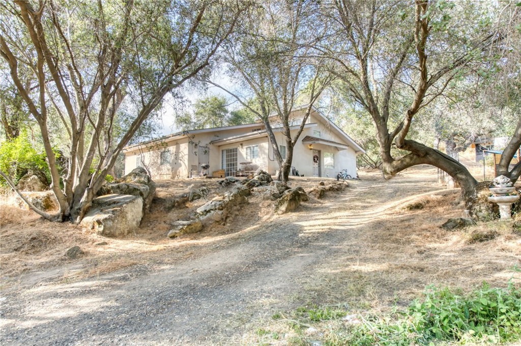 Nestled amidst the breathtaking scenery of rugged foothills of Coaragold, this unique 4-bedroom, 4-bathroom home offers a perfect blend of rustic charm and modern luxury. As you approach the property, a grand entrance framed by lush trees welcomes you, setting the tone for the tranquil elegance that lies within. Recently remodeled with newer flooring. This home has two separate access points and the potential for a second kitchen (plumbing complete). This allows the ability to separate the home into two units each if desired. The over 8 acres of land contains small creeks, extra propane tanks, RV hookups and an extra large metal shop. The possibilites are endless to make this hone your own private oasis.
