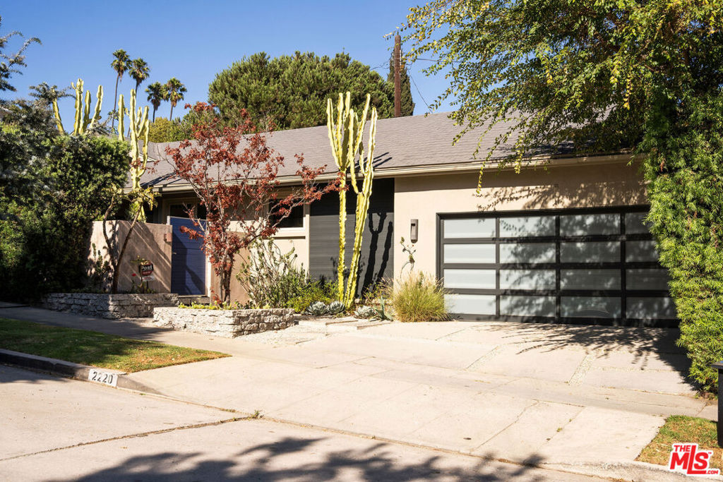 Tucked behind gates, hedges, and a lush tapestry of native, drought-tolerant plants and sculptural cacti, this private mid-century oasis in prime Los Feliz blends timeless design with tranquility. A majestic Japanese maple and zen-like courtyard with a babbling fountain set the tone, while stone paths, gravel walkways, and layered greenery invite you in before you've even stepped inside. The entryway opens to a wide, light-filled layout anchored by rich dark wood floors and a full wall of glass that brings the outdoors in -- true to mid-century ideals. The spacious living room flows into a generous dining area and a custom bar, with a sleek double-sided concrete fireplace offering warmth and subtle separation between spaces.The open kitchen overlooks it all, featuring slate floors, Heath Ceramics tile, limestone island, and an inviting breakfast nook perfect for a quiet morning coffee or catching up over a casual bite. In one wing, the primary suite offers calm and privacy, with oversized sliders that open to the lush front courtyard and a spa-like bath with dual vanity and a deep soaking tub-shower. A second bedroom, almost like a second primary in size, also opens to the backyard. The third bedroom and a stylish hall bath with chic glass tile shower are located in the opposite wing, creating flexibility and privacy for guests or work-from-home needs. Step into the backyard through any of the three large sliding doors and you're in an entertainer's dream -- multiple zones for lounging and dining, including a built-in bench and custom table perfect for unforgettable dinner parties. A private stretch of lawn completes the backyard, ideal for outdoor play or simply soaking up the sun. Additional features include an attached 2-car garage with extra room for storage, a stackable washer/dryer, and a driveway that fits two cars side by side. Located within the coveted Franklin Avenue Elementary school district (per LAUSD). All just moments from Los Feliz Village and an array of local favorites like Alcove, Little Dom's, Lou's Wines, All Time, Encanto, Jeni's, Maru, MessHall and more. Enjoy being minutes from Griffith Park trails, the Observatory, concerts at The Greek and easy freeway access. Welcome home!