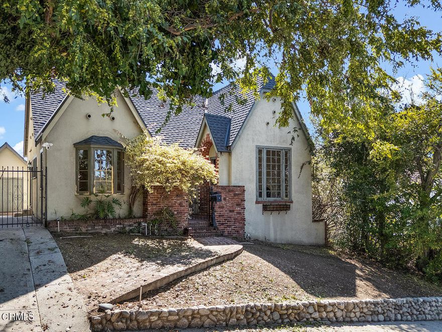 Tucked away on a quiet cul-de-sac in Highland Park, this 1926 Tudor feels like a secret from another era - full of warmth, charm, and possibility. With its pitched roofline, arched entryway, and textured stucco, the home's character is undeniable, waiting patiently for its next chapter to unfold.Inside, a coved ceiling and decorative fireplace anchor the living room, where light pours through a large window overlooking the front yard. The dining room, framed by an arched doorway, features French windows that open to the front porch, along with a charming corner built-in and original hardwood floors. Throughout the home, small details like arched niches, hardwood floors, and wood-frame windows hint at the enduring style of 1920s design.Both bedrooms share a hall bath and enjoy natural light and backyard views, while front and rear yards offer views of the mountains and the hills of Highland Park. The exterior is a blank canvas, ready for new gardens, patios, or outdoor living spaces. The roof has already been replaced, providing a solid foundation for future restoration. The one-car garage and long driveway have plenty of space off-street parking and storage, while the cul-de-sac setting provides a sense of peace away from the hustle and bustle of the city.Private yet connected, the location offers the best of both worlds - equidistant to Eagle Rock and Highland Park, with easy access to shops, cafes, and the freeway. For those who appreciate history, architecture, and a worthy project, this 1926 Tudor is ready to shine once again.