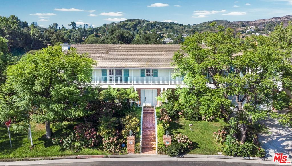 Set on nearly half an acre in a private, picturesque setting, this six-bedroom estate offers both grandeur and versatility for families seeking space, comfort, and lifestyle. Designed with a rare second-floor dual-wing layout, the residence balances expansive outdoor entertaining areas with future expansion possibilities ideal for a large or extended family.A gracious foyer with soaring ceilings and an elegant chandelier opens to a sunlit living room anchored by a full wet bar, perfect for celebrations large or small. The formal dining room sits adjacent to a chef's kitchen, featuring an oversized stone island, expansive countertops, dual workstations, a six-burner cooktop, two sets of double ovens, and two dishwashers more than ample to make both weekday dinners and gala soires a breeze. An executive den with built-in wood cabinetry offers canyon and mountain views, providing the perfect perch for work or contemplation.The grand staircase leads to a vaulted second-story foyer, flanked by a three-bedroom wing with en-suite baths, built-ins, and a shared lounge area. Dividing the space is an upstairs gym with a sauna, while the other wing accesses the theatre like media room and the primary suite. The master suite features a sitting area, the master bedroom has vaulted ceilings and an expensive view, wood-burning fireplace, balcony access through French doors, and a spa-inspired bathroom with a jetted tub, rain steam shower with seating, dual vanities, and dual closets comfort, privacy, and indulgence all in one.The grounds are equally impressive, with a resort-style pool and spa framed by natural stone, a sport court, multiple terraces for entertaining, a built-in barbecue, and lush, mature landscaping ensuring privacy. Beyond the sports court, an additional expanse of land invites future enhancements a guest house, expanded terraces, or even a second residence. This beloved estate has been the backdrop for years of memorable gatherings and cherished family life. Now it awaits its next chapter. With a fresh designer's eye, updated colors, and modern textures reflecting today's palette, this home offers an extraordinary opportunity to reimagine its grand spaces while preserving the scale, amenities, and character that make it truly remarkable.