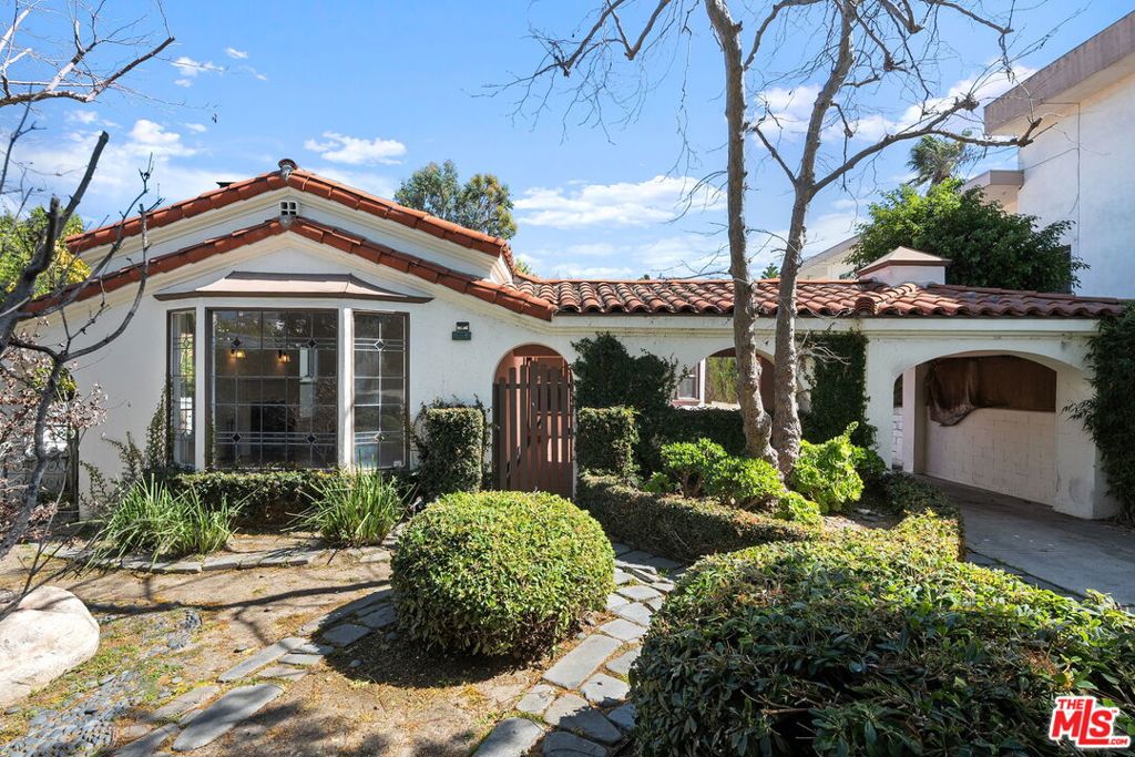 Welcome to 1904 S Shenandoah, a charming Steinkamp-style home nestled in the highly desirable Crestview neighborhood. Located in a serene and sought-after area, this 3 bedroom, 2 bathroom home greets you with a spacious cobblestone front yard framed by mature trees, a charming courtyard, and a secure gated driveway. Inside, the living room radiates warmth with its brick fireplace, large paned windows, recessed lighting, and distinctive arched ceiling. Beautiful hardwood floors seamlessly flow into the light-filled dining area, which is adorned with stunning crown molding that enhances the home's original character. The kitchen is a true standout, featuring top of the line stainless-steel appliances, stone countertops, and ample cabinetry for all your culinary needs. A nearby laundry room offers convenient access to the outdoors. The primary bedroom boasts custom built-ins, private access to the elevated patio, and an en-suite bathroom with dual vanities. Step outside to the expansive backyard, featuring a detached garage and a spacious patio-perfect for al-fresco dining or unwinding under the stars. Additional notable features include hardwood floors throughout, large stained glass windows that flood the spaces with natural light, and a large basement providing versatility for your needs-ideal for a home office, children's playroom or extra living space for guests. With a prime location near schools, parks, dining, and entertainment, this home embodies the quintessential Los Angeles lifestyle. LAR2 zoning.
