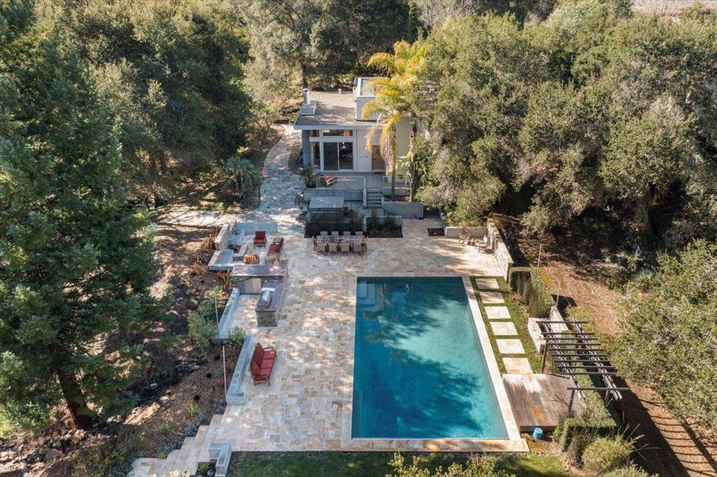 MAGICAL OASIS WITH ARCHITECTURAL MASTERPIECES | Nestled on a private drive, this natural paradise crowned by two architecturally spectacular structures is made even more exclusive by its stunning canyon setting. The main house is defined by a cathedral-like gallery that spans the sleeping and gathering wings, while multiple decks overlook the scenic surrounding grounds. Enjoy a stylish remodeled kitchen, plus a serene primary suite remodel with private deck, multiple closets, quartz countertops, and GAIA Picchi luxury floors. The home includes an office/potential 4th bedroom, and studio with full workshop (may convert to bedrooms). Steps lead to a fully functional guesthouse with 2 bedrooms (incl. 1 loft), full bath, fireplace, decks, and gourmet kitchen sharing soaring ceilings with the living room. Joining the two homes is a grand entertaining area with large stone patio, luxurious 40 pool and auto cover, new separate spa, BBQ kitchen, shower, and entertaining terraces. A vibrant forest of oaks, cedars, and rare palms enhances the grounds, which offer an amphitheatre, manzanita xeriscape garden, access to an irrigation aquifer, and private trails into adjacent nature preserves. Max floor area of 12,650 SF; Palo Alto schools (buyer to confirm).