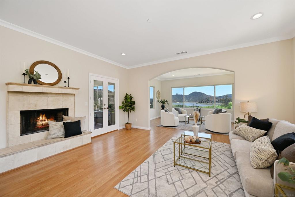 Experience stunning panoramic views of Lake Hodges from this elegant hillside retreat. This beautifully crafted home captures the essence of tranquility and natural beauty, offering breathtaking vistas from the main living areas, bedrooms, and the private top-floor suite. Set in a peaceful, rural setting surrounded by nature, this property provides a serene escape just minutes from modern amenities. Enter to discover warm, inviting interiors filled with natural light. Crown molding, arched doorways, and rich flooring complement large windows that frame the scenic outdoors. The entry level features a spacious living room with fireplace, a comfortable bedroom suite, an office or den, and an enclosed patio perfect for year-round relaxation. Downstairs, enjoy an upgraded kitchen and an expansive dining room ideal for entertaining. French doors open to the backyard, where you can dine alfresco and take in the views. A full bathroom and large laundry/utility room complete the lower level. Upstairs, the private suite boasts a walk-in closet and full bathroom, creating the perfect personal retreat and a picturesque lake view. The home is all-electric with an owned 24 panel solar system for energy efficiency and long-term savings. With nearby hiking and biking trails, this serene oasis offers a lifestyle of peace, privacy and outdoor adventure providing the best of both nature and convenience. Don't miss this rare opportunity to own a truly special home with breathtaking lake views!