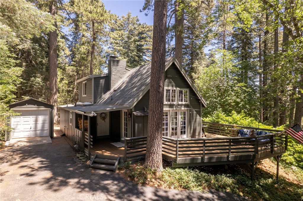A storybook cottage nestled in the heart of Skyforest, offering timeless rustic charm amongst towering pines and majestic cedars. This 3-bedroom, 2-bathroom retreat sits in a peaceful, wooded setting with unmatched privacy.
Step into the warm and inviting living room featuring a dramatic vaulted ceiling with exposed log accent beams, skylights that flood the space with natural light, and a cozy wood burning stone fireplace. Savor the beautiful views of the forest from the kitchen's large picture windows. The entry level boasts two well appointed bedrooms, of which one has separate entry to the back yard, a full bathroom and laundry room. Upstairs is the primary suite with a Juliette balcony that overlooks the living room below and an ensuite, full bathroom.
Enjoy outdoor living year-round on the composite deck, ideal for relaxing or entertaining under the trees. A detached garage provides great storage or workshop potential, and a backup generator offers peace of mind during mountain weather. Other upgrades include dual pane Milgard windows, a mini-split air conditioner in the primary bedroom,a newer furnace and the home was re-piped in 2020.
This is a rare opportunity to own a piece of Skyforest magic — where rustic charm meets modern comfort in a truly private, forested setting.