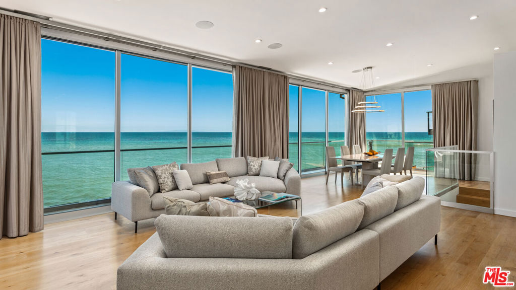 This fully refreshed coastal retreat combines sweeping ocean views with turnkey luxury. Brand new furnishings, fresh paint, a newly installed dishwasher, and full professional disinfection ensure a pristine move-in experience. The gated driveway accommodates up to six cars, and every detail down to the towels, linens, and even the cups is brand new. A whole-house water filtration system delivers clean, drinkable tap water throughout. Enter through the front door into an open-concept main living space with wide wood floors, soaring ceilings, recessed lighting, and a coat closet. The ocean pulls you in immediately with panoramic views through sliding glass doors. To the left, the chef's kitchen features a Sub-Zero fridge/freezer, KoolMore dishwasher, water-filtered sink, Viking oven with six-burner range and hood, built-in cabinetry with pull-out pantry drawers, and a microwave. A bar counter offers seating, while a window behind the sink opens to capture the ocean breeze. A door leads directly to the main deck. The adjacent living room enjoys equally dramatic views, anchored by hardwood floors, recessed lighting, and a built-in speaker system. Sliding glass doors open to an expansive oceanfront deck 100 feet of beach frontage with dining and lounge areas, remote-controlled curtains, and storage for outdoor cushions. Catalina views stretch across the horizon. The dining area blends seamlessly into the main living space, offering a stunning backdrop of sea and sky with access to a view balcony. The main-level bedroom features wood floors, recessed lighting, built-in closets, and direct access to a dual-entry bathroom with illuminated vanity, rainfall shower, and warm wood finishes. A sliding wood door connects bedroom and bath for privacy and flow. Downstairs, the oceanfront primary suite is a private sanctuary. Sliding glass doors open to multi-tiered decks with panoramic views. Wood floors, recessed lighting, built-in dressers, an integrated speaker system, and automatic shades create a serene retreat. The en suite primary bath offers ocean views from a freestanding tub, double vanity with illuminated mirrors, a bidet, and a glass shower that opens directly to the deck. A detached guest suite offers a peaceful escape with tile floors, sliding doors, beamed ceiling, built-in desk, and ocean views. The en suite bath features marble walls, tile flooring, a sleek vanity, and shower. Additional highlights include a laundry room with abundant storage and a spacious closet with built-ins. A bonus room that's ideal for a gym, studio, or office and features wood floors, recessed lighting, a dining nook, speaker system, and accordion glass doors that frame city views. Outdoor amenities include multiple oceanfront decks, high-end outdoor furniture, an Egg grill, kayaks, security cameras, and a fully integrated smart home system. Every inch of this property has been elevated for comfort, luxury, and functionality, and ready for immediate enjoyment.