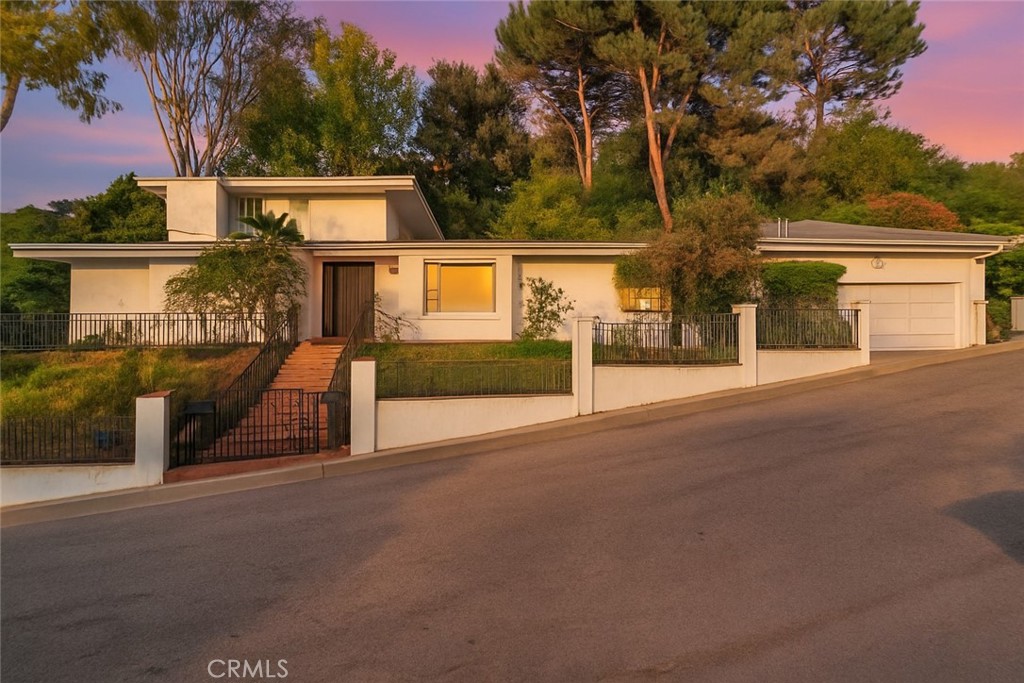 Perched in the hills south of Ventura Blvd, this expansive, 5 bed, 3.5 bath, nearly 4000 sq ft, gated residence offers sweeping mountain and valley city views. Designed for versatile living and entertaining, the home has a spacious, open layout and thoughtful design. Fresh paint and new carpet throughout! Distinctive double door leads into a light-filled interior with open floorplan and generous living spaces. Family room is anchored by sleek black fireplace and framed by a wall of windows that perfectly capture the breathtaking views, while built-ins adds both function and sophistication. The formal living room is perfect for entertaining with full wet bar and generous bay window. Adjacent dining room offers sliding glass door access to the back patio and seamlessly connects the space with the kitchen beyond. A bold, statement kitchen is outfitted with a 6-burner Thermador range, double ovens, black granite counters, and a convenient passthrough. The main level boasts a convenient guest powder bath, dedicated utility room with laundry hookups, and 3 bedrooms. 1 bedroom is an impressive secondary suite with large dressing area, dual closets, and luxurious, full, en-suite bath with dual sink vanity and separate soaking tub and shower. Another offers an en-suite ¾ bath, built in shelving, and direct access to the yard. The third has extensive built-ins, including a desk, that would be a perfect home office or library. Upstairs are 2 additional bedrooms, including the primary suite, with high vaulted ceilings and bay windows to enjoy to spectacular view. The lavish primary has a truly impressive walk-in closet with custom built-ins and a luxurious bath with jetted tub, walk-in shower with multiple heads, and dual sink vanity. Outside is a wraparound brick walkway leading to patio space and seating areas designed to maximize enjoyment of the privacy and view. A sparking pool and spa complete the yard space, making it perfect for quiet contemplation or a backyard bash! Additional features include dual zone HVAC and an attached 2-car garage with lofted storage area. Located moments from Sherman Oaks' best dining, shopping, and lifestyle destinations, this is a rare opportunity to own an exceptional home in highly sought-after Longridge Estates neighborhood, just minutes from both valley and Westside destinations. With its commanding views, smart layout, and exceptional privacy, you don’t want to let this hillside retreat pass you by!