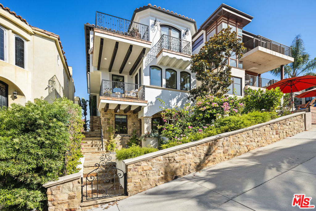 229 24th Street offers the perfect balance of refined coastal living and breathtaking panoramic ocean views, ideally situated on a coveted south-facing Walk Street. Custom-built in 2009 with over 4,100 square feet of thoughtfully designed interior living space, this residence features five bedrooms and four-and-a-half baths, blending timeless craftsmanship with modern functionality. Every detail reflects quality and elegance, from the custom millwork, wrought iron accents, and walnut floors to antique French pavers, Kolbe & Kolbe exterior-clad windows, and solid Alder doors. The home's scale and natural light create a warm yet sophisticated atmosphere throughout. The top floor is designed for seamless entertaining with an open-concept layout featuring a chef's kitchen, expansive living and dining areas, and two separate patios framing dramatic ocean vistas. The primary suite is a private retreat complete with a spa-inspired bath and its own ocean-view patio, while three additional bedrooms on the second level offer generous scale, one with an en-suite bath. The ground level provides versatility and comfort with an additional guest bedroom, full bath, family room opening directly to the Walk Street patio, and a three-car garage with abundant storage. A convenient three-stop elevator connects all levels with ease. Lushly landscaped front yard with firepit is elevated to take advantage of the views .Perfectly located just two blocks from the sand and a short stroll to downtown Manhattan Beach, this home combines luxury, lifestyle, and location into a rare offering.