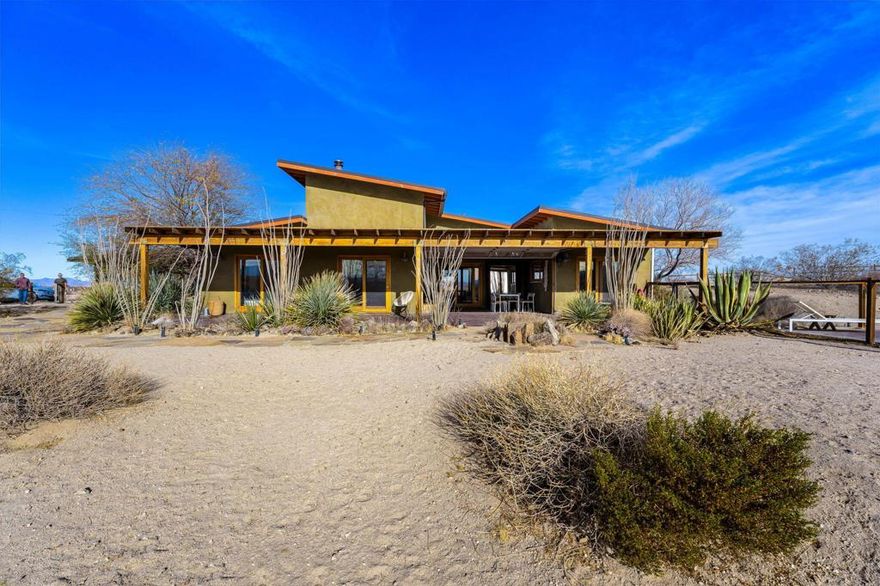 This established Airbnb retreat in Coyote Valley offers two unique homes on 10 acres, each with stunning desert views, a private in-ground pool w/ gazebo, multiple spas, owned solar, fire pits, and a strong rental history.  Most of the surrounding land is untouched BLM and Conservancy land of nearly 1,000 acres minus the adjacent famous Mojave Rock Ranch.The first home, a 1965 vintage retreat, features two bedrooms, one bath, reflection glass portals, a fire pit, and an above-ground spa, surrounded by Joshua Trees and a serene reflection pool. Guests love its artistic flair and privacy.The second home, a modern architectural abode, boasts soaring ceilings, a spacious open kitchen, and a wraparound porch with breathtaking views. It includes two bedrooms (one en suite) and a half bath, plus a private spa overlooking the desert.  An oversized roll down glass door helps bring the outside in.  Between the homes, enjoy a private in-ground pool and lounging area.  Additionally there is finished garage space with office allowing for flexibility - The 10-acre lot (two 5-acre parcels) offers seclusion yet is minutes from 29 Palms and Joshua Tree Village, with easy access to boulders and the Transmission sculpture by Daniel Popper.A proven Airbnb favorite, this property comes with rental history, guest reviews, and the Airbnb portal for a seamless transition. Don't miss this rare opportunity with a second lot for expansion - create your dream family compound.  Schedule a private viewing today!  Sale includes two parcels APN: 0632-091-05 and 0632-091-06.