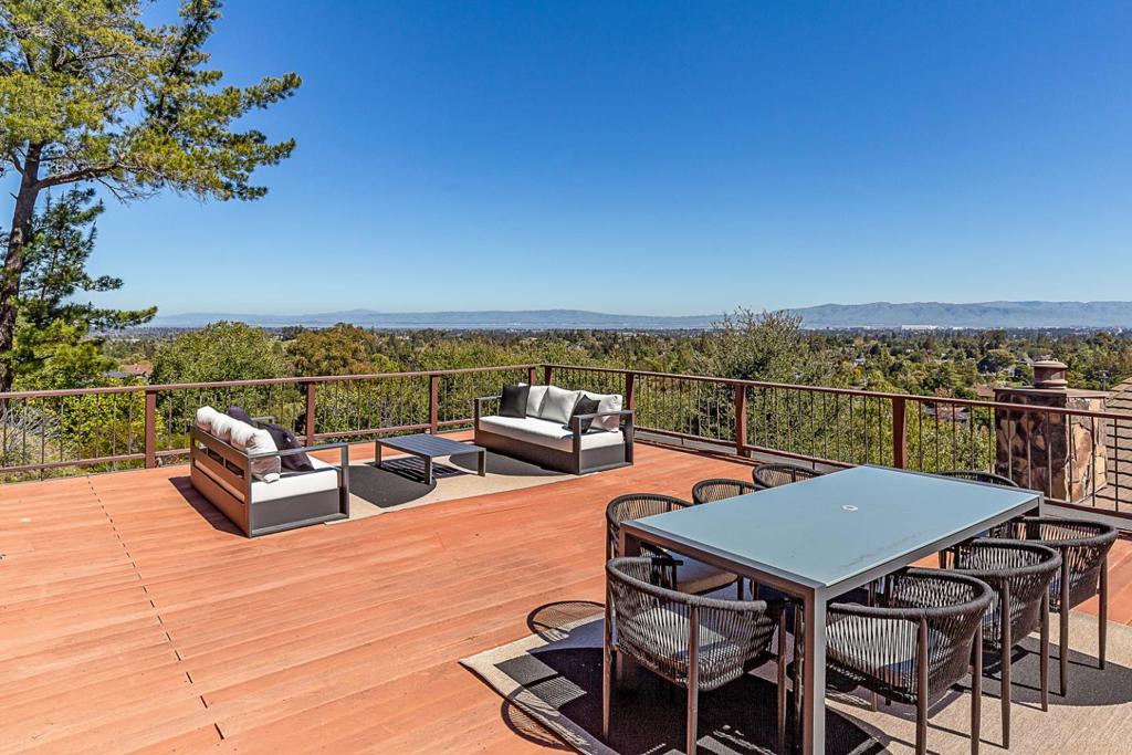 Set on a tranquil 1.5-acre parcel in one of the most sought-after pockets of Los Altos Hills, this beautiful mid-century home offers the extremely rare blend of panoramic Bay views, exceptional privacy, close proximity to the Village, and acclaimed Palo Alto schools. The interior blends timeless architectural character with modern updates, and includes generous entertaining spaces, seamless room-to-room connection, and expansive windows that each present a different vantage point of the breathtaking views. The main-level primary suite offers a serene retreat with extensive closet space, an updated spa-inspired bath, coffee bar, and private outdoor access. There are three additional bedrooms, one with an en suite bathroom, one with an adjoining office, and all with access to the outdoors. A state-of-the-art media/recreation room with projector, retractable cinema screen, full bar, and wine cellar provides the ultimate in-home experience. Exterior amenities include upper and lower view decks, a very large rooftop entertainment space with panoramic views, a spacious front patio, and a level lawn perfect for recreation and play. Peaceful Silicon Valley living, ideal for those who value space, style, views, and access to world-class education!