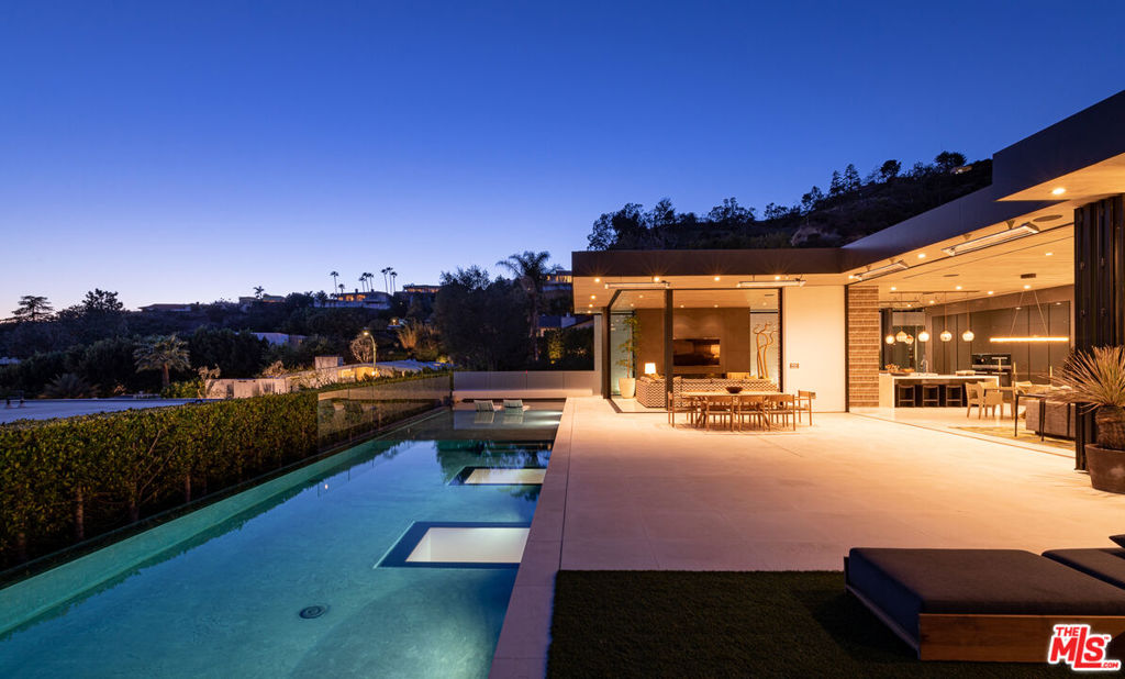 Soaring above Sunset Blvd with jetliner views from Century City to the pacific ocean, this furnished modern showcases breathtaking unparalleled views of Los Angeles. This home boasts 12-foot ceilings, floor to ceiling windows, multiple water features, car museum and a 70-foot book-matched marble exterior wall for ultimate privacy. The open-plan living areas take you through expansive Fleetwood doors leading you to the sun-lit deck and infinity pool. Chef's style kitchen and primary suite with spacious walk-in closet and master bath on main level. Second suite with optional second entrance on main level. A daylit entertainer's level holds 2 additional en-suite bedrooms, a great room with custom bar, 18 seat screening room, fitness room with steam, and a lounge space. With full Crestron automation, this home offers a living experience moments to the Beverly Hills Hotel and Rodeo Drive. Please inquire with agent about available concierge services for an extra fee.