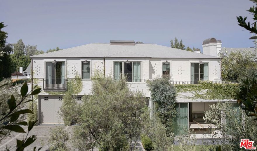 Located in prestigious Brentwood Park on one of its most desirable streets, 127 South Burlingame Avenue is a gated estate offering 9,000 square feet of custom-built living space across two levels. Set on a 19,406-square-foot lot, the home features seven ensuite bedrooms, each with a private terrace. Thoughtfully designed and built by Muskoka Living's Cory DeFrancisco as a personal residence, the home reflects his signature approach to livable luxury and embodies the California lifestyle. Layered, organic design, abundant natural light and a soft, tonal color palette all work in quiet harmony for an effortless feel. Yet every detail was meticulously considered and crafted, with a focus on gently arched, organic forms throughout and aligned materials across rooms to create continuity. Soaring, 12.5-foot ceilings, rustic oak flooring, wire-brushed poplar and fluted wood paneling, and layered stone lend warmth and sophistication throughout the home. Nearly every piece, from furniture to cabinetry, flooring and lighting, was designed and fabricated in-house by Muskoka Living. The result is a relaxing and seamless flow from formal entertaining spaces on the main level to an open-concept family room and kitchen with bespoke, pale oak cabinetry and an arched wet bar in the dining area. A curved kitchen island is topped with beautifully veined, Calacatta Reclusa marble countertops, and a showstopping set of custom-designed white pendant lights, whose repeated circular motifs echo other curved forms in the home. Matching marble backsplash and top-tier, professional-grade appliances complete the elegant space. Outside, a modern, Santa-Barbara-inspired landscape design is layered with an East Coast sensibility, featuring clean lines, Italian black granite pavers and low-maintenance hardscaping. Mature olive and citrus trees frame a sunlit backyard that's anchored by a pool and spa, with a detached, poolside guest house, and a sports court. A finished three-car garage and ample gated driveway parking complete the property. Located just moments from Brentwood Country Mart and Brentwood Country Club. Known for its wide, tree-lined streets, large estate lots, and timeless appeal, Brentwood Park is centrally located for easy access to Los Angeles' premier dining, shopping and lifestyle offerings. The setting is both peaceful and central, offering a rare blend of privacy and proximity to the best of the Westside.