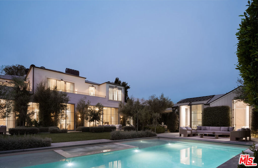 Located in prestigious Brentwood Park on one of its most desirable streets, 127 South Burlingame Avenue is a gated estate offering 9,000 square feet of custom-built living space across two levels. Set on a 19,406-square-foot lot, the home features seven ensuite bedrooms, each with a private terrace. Thoughtfully designed and built by Muskoka Living's Cory DeFrancisco as a personal residence, the home reflects his signature approach to livable luxury and embodies the California lifestyle. Layered, organic design, abundant natural light and a soft, tonal color palette all work in quiet harmony for an effortless feel. Yet every detail was meticulously considered and crafted, with a focus on gently arched, organic forms throughout and aligned materials across rooms to create continuity. Soaring, 12.5-foot ceilings, rustic oak flooring, wire-brushed poplar and fluted wood paneling, and layered stone lend warmth and sophistication throughout the home. Nearly every piece, from furniture to cabinetry, flooring and lighting, was designed and fabricated in-house by Muskoka Living. The result is a relaxing and seamless flow from formal entertaining spaces on the main level to an open-concept family room and kitchen with bespoke, pale oak cabinetry and an arched wet bar in the dining area. A curved kitchen island is topped with beautifully veined, Calacatta Reclusa marble countertops, and a showstopping set of custom-designed white pendant lights, whose repeated circular motifs echo other curved forms in the home. Matching marble backsplash and top-tier, professional-grade appliances complete the elegant space. Outside, a modern, Santa-Barbara-inspired landscape design is layered with an East Coast sensibility, featuring clean lines, Italian black granite pavers and low-maintenance hardscaping. Mature olive and citrus trees frame a sunlit backyard that's anchored by a pool and spa, with a detached, poolside guest house, and a sports court. A finished three-car garage and ample gated driveway parking complete the property. Located just moments from Brentwood Country Mart and Brentwood Country Club. Known for its wide, tree-lined streets, large estate lots, and timeless appeal, Brentwood Park is centrally located for easy access to Los Angeles' premier dining, shopping and lifestyle offerings. The setting is both peaceful and central, offering a rare blend of privacy and proximity to the best of the Westside.
