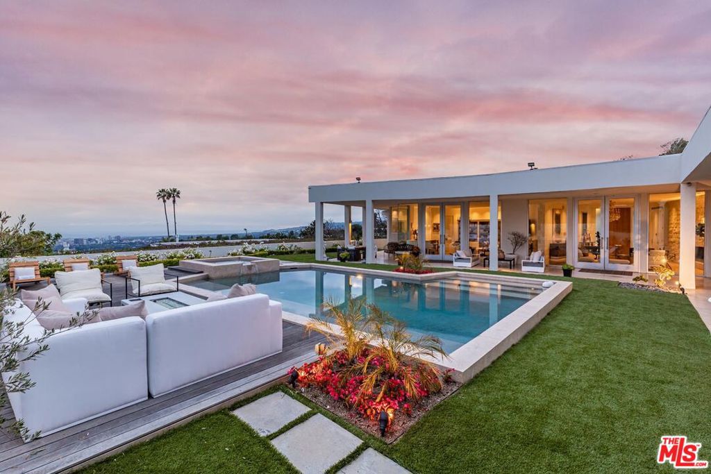 Nestled within an exclusive enclave of Trousdale Estates, this quintessential mid-century modern epitomizes refined elegance. The residence effortlessly blends contemporary aesthetics with timeless sophistication, creating a harmonious fusion of the best of both worlds. Beyond the private gates, you'll discover opulent open living spaces adorned with the finest materials sourced from around the globe. Step onto the timeless Terrazzo floors, perfectly complemented by exotic hardwoods, and immerse yourself in rooms bathed in natural light pouring in from floor-to-ceiling glass doors. This open floor plan gracefully extends into the outdoor living areas, where an expansive backyard oasis awaits, complete with an oversized pool that offers breathtaking panoramic views stretching from the city to the ocean.As the day draws to a close, retreat to the epitome of luxury living the Primary Suite, a magnificent sanctuary spanning an impressive 2000 square feet. Indulge in the opulence of this expansive bedroom which boasts a cocktail bar, spa-like facilities, a rejuvenating steam room, and his-and-her walk-in closets. Prepare to have your dreams transformed into reality in this extraordinary masterpiece nestled high above the twinkling city lights.