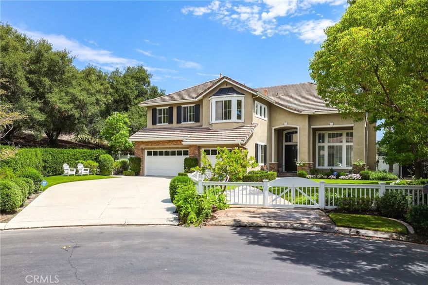 Located within the prestigious 24-hour guard-gated community of Coto de Caza, this 5-bedroom, 4.5-bath residence offers 4,000 sq. ft. of living space on a rare 30,000+ sq. ft. corner lot. Tucked at the end of a double cul-de-sac with no homes directly behind, the property ensures exceptional privacy while capturing picturesque views of Coto de Caza’s natural surroundings. The expansive lot presents endless possibilities—whether for an ADU, outdoor entertaining, or resort-style recreation—making this one of the community’s most coveted settings. A charming white picket fence frames the front yard and leads to an impressive double-door entry, introducing the home’s refined character. Inside, the spacious floor plan is defined by soaring ceilings, intricate crown moldings, and custom millwork that elevate timeless sophistication. The main level features a versatile executive office or bedroom with built-ins and adjacent full bath, a formal living and dining room, and a convenient laundry room with direct access to the three-car garage. The gourmet kitchen opens seamlessly to the family room and backyard, creating a perfect flow for everyday living and effortless entertaining. Upstairs, a generous landing connects the secondary bedroom suite, third bedroom, and versatile bonus room to the luxurious primary retreat. The primary suite boasts dual vanities, a walk-in closet, and a beautifully appointed bath. A private balcony captures the home’s most breathtaking views. The spacious secondary suite overlooks the front yard with its own full bath, while the third bedroom shares a Jack-and-Jill bath and features hardwood flooring and serene tree-lined views. The bonus room adds flexibility as a den, playroom, or fifth bedroom. Outside, the backyard is a true retreat with a sparkling pool and spa, outdoor fireplace, built-in grill, and captivating views of the rolling hills. Beyond the property, Coto de Caza offers an unparalleled lifestyle with miles of scenic trails for hiking, biking, and horseback riding, along with golfing, tennis, aquatics center, parks, sports courts, and open spaces that encourage an active lifestyle. The prestigious Coto de Caza Golf & Racquet Club provides endless opportunities for recreation and community connection. Combined with award-winning schools, this rare setting blends luxury, privacy, and convenience in one of Orange County’s most desirable destinations.