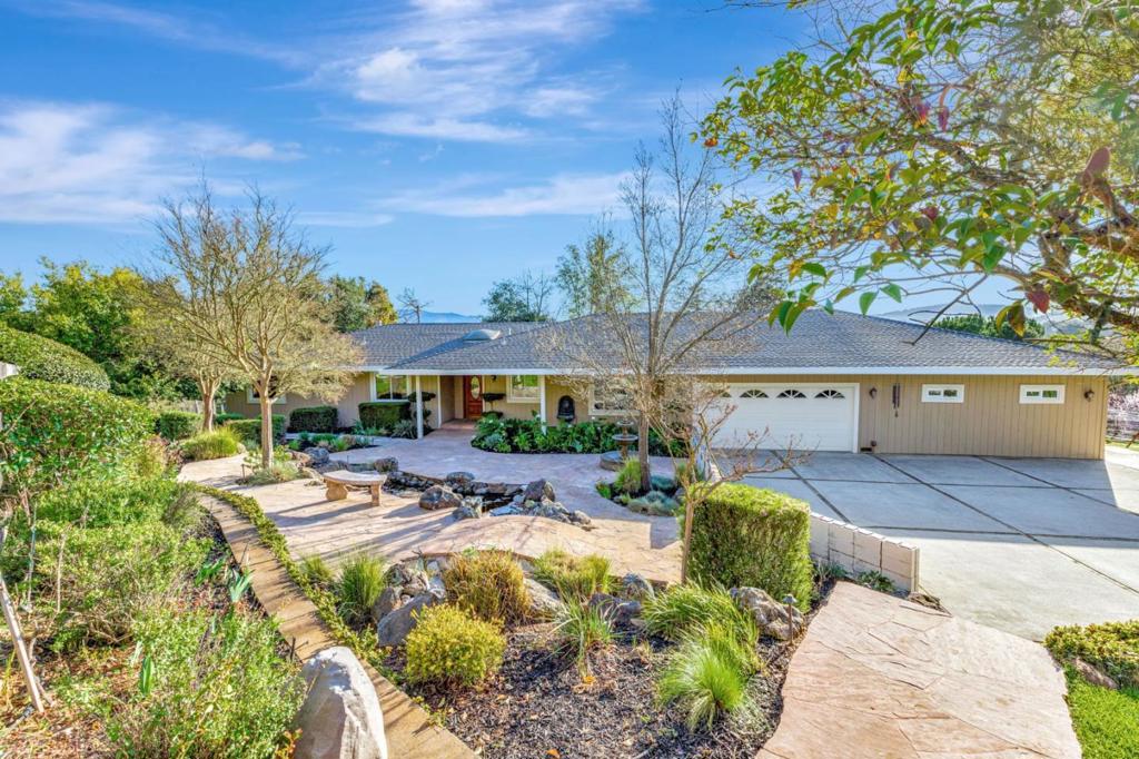 Experience the perfect blend of luxury, privacy, and natural beauty in this exceptional single-story home on expansive acreage with panoramic views and stunning sunsets. Designed for both relaxation and entertaining, it features a warm, inviting interior, resort-style outdoor spaces, and your own vineyard. A gated entry welcomes you along a picturesque driveway lined with blooming cherry trees, leading to a serene water garden and ample parking. Inside, the light-filled open floor plan showcases wood flooring, updated kitchen and bathrooms, and a spacious great room with a fireplace, wine bar, and double sliders opening to a Trex deck. The split layout includes two ensuite bedrooms, ideal for families or guests. The home also includes an additional approximately 500 square feet of living space from a converted spare garage. The backyard is a true retreat, featuring a tranquil koi pond, gazebos for shaded seating, and a fire pit. Nestled among rolling green hills and mature trees, this home offers a peaceful lifestyle with modern amenities and the benefit of owned solar. Conveniently located just 10 minutes from shops and schools, about 30 minutes from San Jose Airport, and near renowned wineries, this extraordinary property is a rare find.