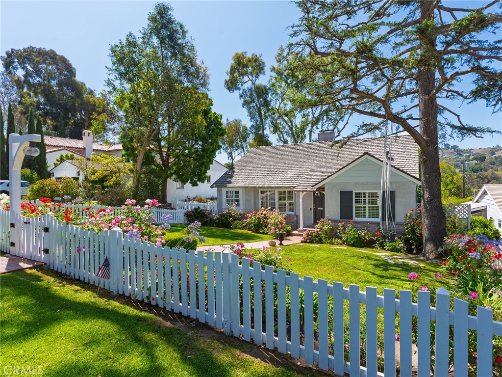 This home comes complete with a white picket fence in the heart of Valmonte and blends timeless charm with modern amenities. A lush front yard and blooming roses welcome you into a warm interior featuring hardwood floors, custom shutters, and elegant moldings. The formal living and dining rooms are perfect for entertaining. The bright kitchen offers white cabinetry, granite counters, stainless steel appliances and a cozy breakfast nook. The adjacent family room with beamed ceilings, opens to a covered deck with scenic treetop views.
The main level includes two spacious bedrooms and a classic hall bath. Upstairs, an office nook and private ensuite bedroom offer an ideal retreat. The lower level features a laundry room, second family room with built-ins, a beverage center, additional bedroom, and access to a large grassy yard with trail access. At the end of the the long driveway, there is also a detached spacious two car garage for parking or extra storage. All in close proximity to schools, the beach, shops and restaurants in the Riviera Village!
A rare blend of space, character and location in sought-after Palos Verdes Estates.