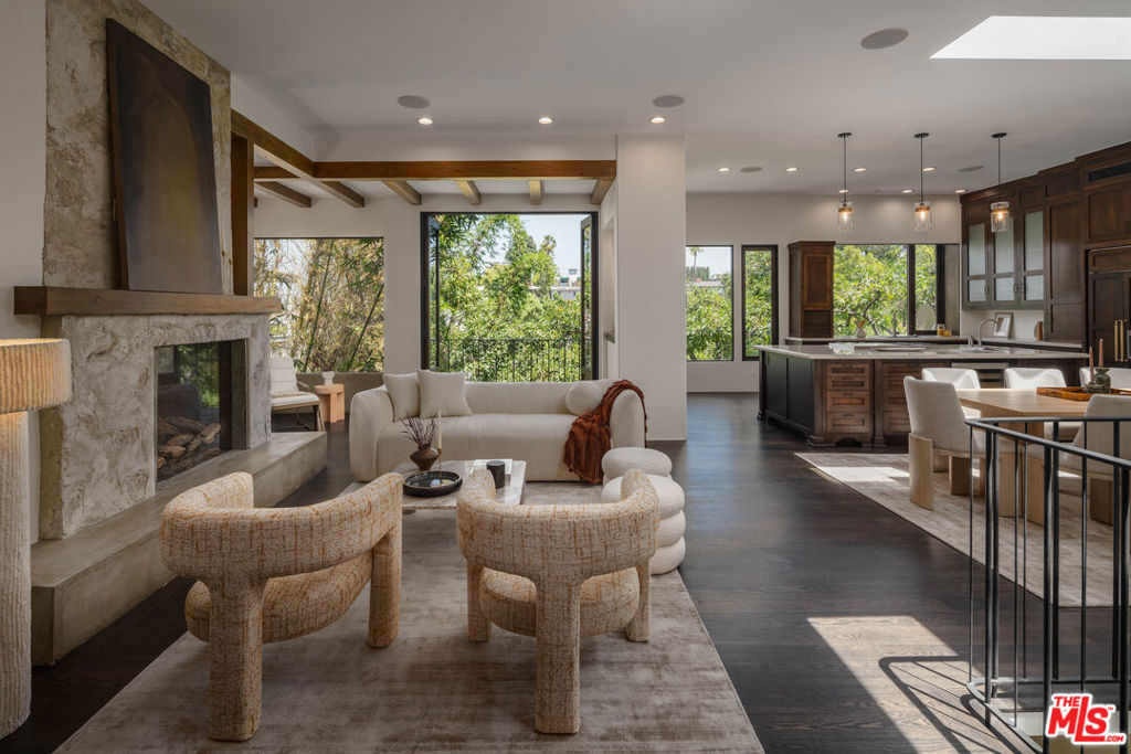 Set in the coveted Franklin Hills, 2444 Lyric Avenue is a striking contemporary retreat that has quietly attracted creatives and tastemakers seeking refined design, serene surroundings, and seamless indoor-outdoor living. Renovated with intention and no expense spared, this serene hillside home is wrapped in lush landscaping and curated for both relaxation and entertaining. Step into the main living area where soaring 12-foot ceilings and expansive windows flood the space with natural light. The open-concept layout flows seamlessly into a sleek chef's kitchen outfitted with high-end appliances and custom cabinetry ideal for modern living and effortless hosting. The expansive primary suite feels like a private retreat, featuring a fireplace, custom walk-in closet, and a spa-inspired ensuite with a soaking jacuzzi tub and glass-enclosed shower. French doors open to a 20-foot balcony surrounded by mature avocado trees, creating the perfect perch for peaceful mornings or golden hour sunsets. Designed with detail at every level, the home features multiple private sun decks, an integrated indoor-outdoor sound system that spans from the living areas to the bedrooms and down to the pool, solar panels and thoughtful architectural touches throughout. Outside, the backyard transforms into a resort-like sanctuary with a lap pool, spa, tranquil rock water wall, and a wine cellar with an adjacent lounge area perfect for entertaining. A dedicated outdoor bathroom and shower add convenience and comfort, elevating every moment spent lounging or entertaining outdoors. A rare offering in one of L.A.'s most beloved hillside neighborhoods, this contemporary retreat embodies comfort, calm, and California living at its finest.